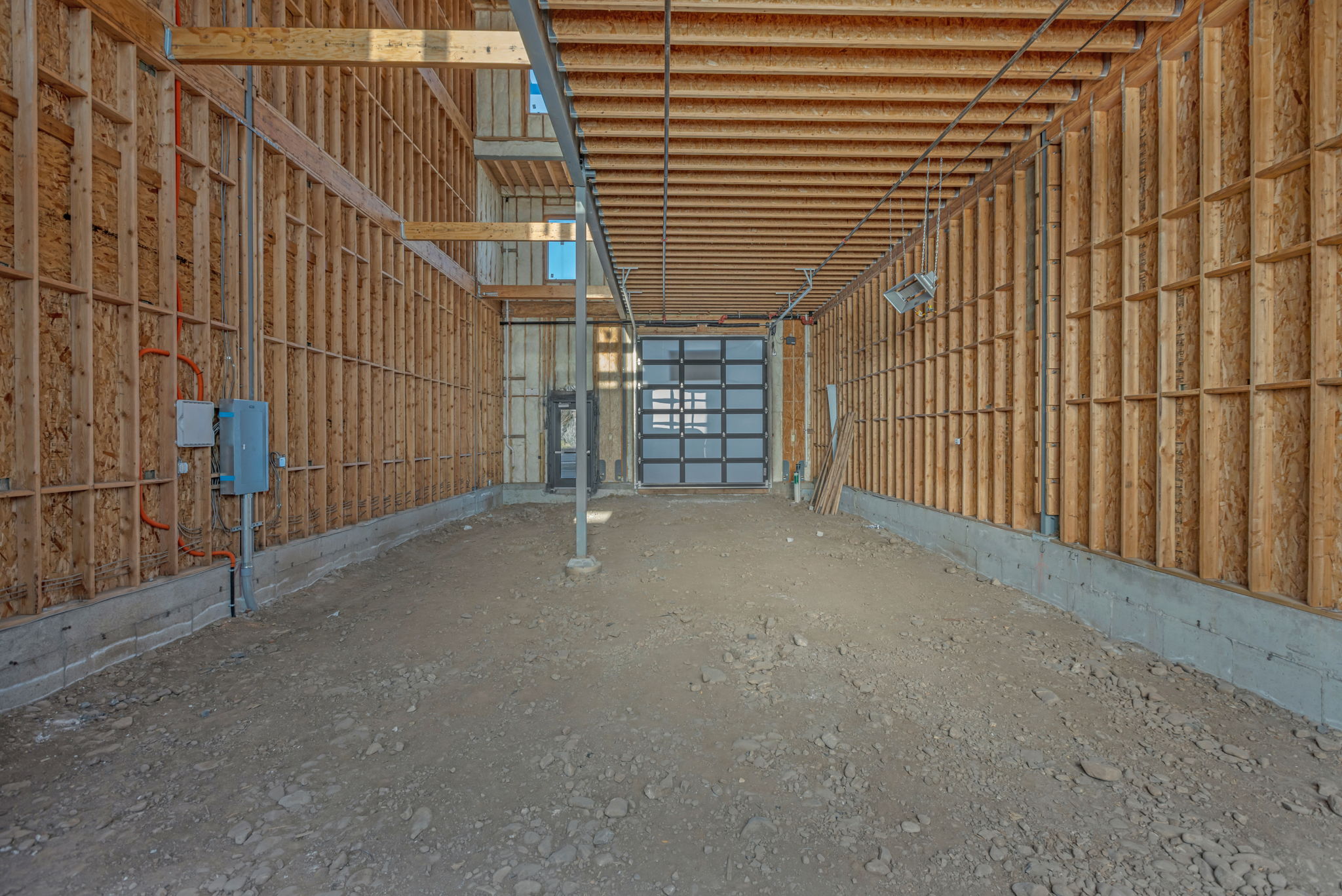 Unfinished interior space featuring exposed wood framing, concrete foundation, and a translucent panel garage door