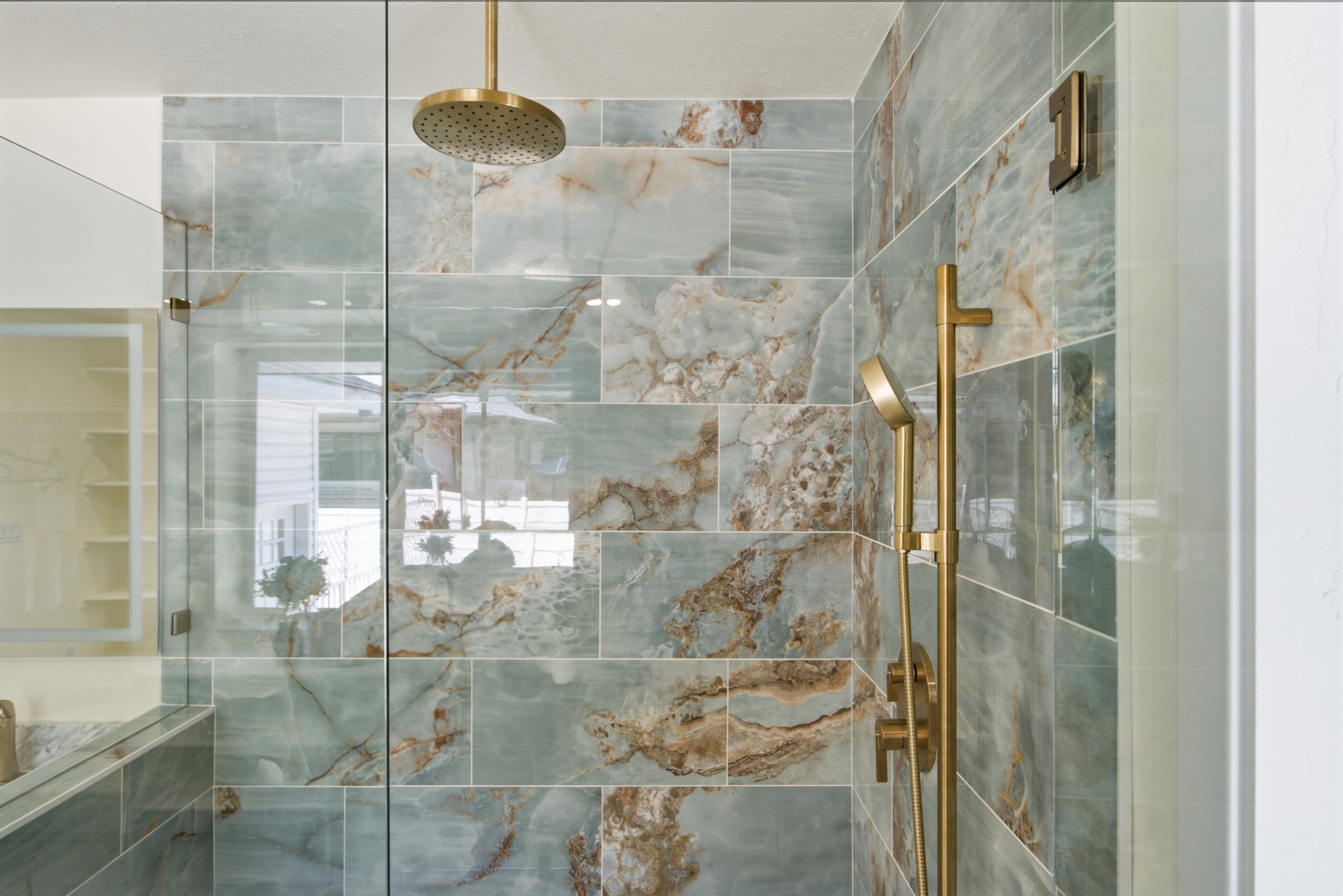 Shower enclosure featuring full-height glass panels and blue-green marbled tile with brown accents