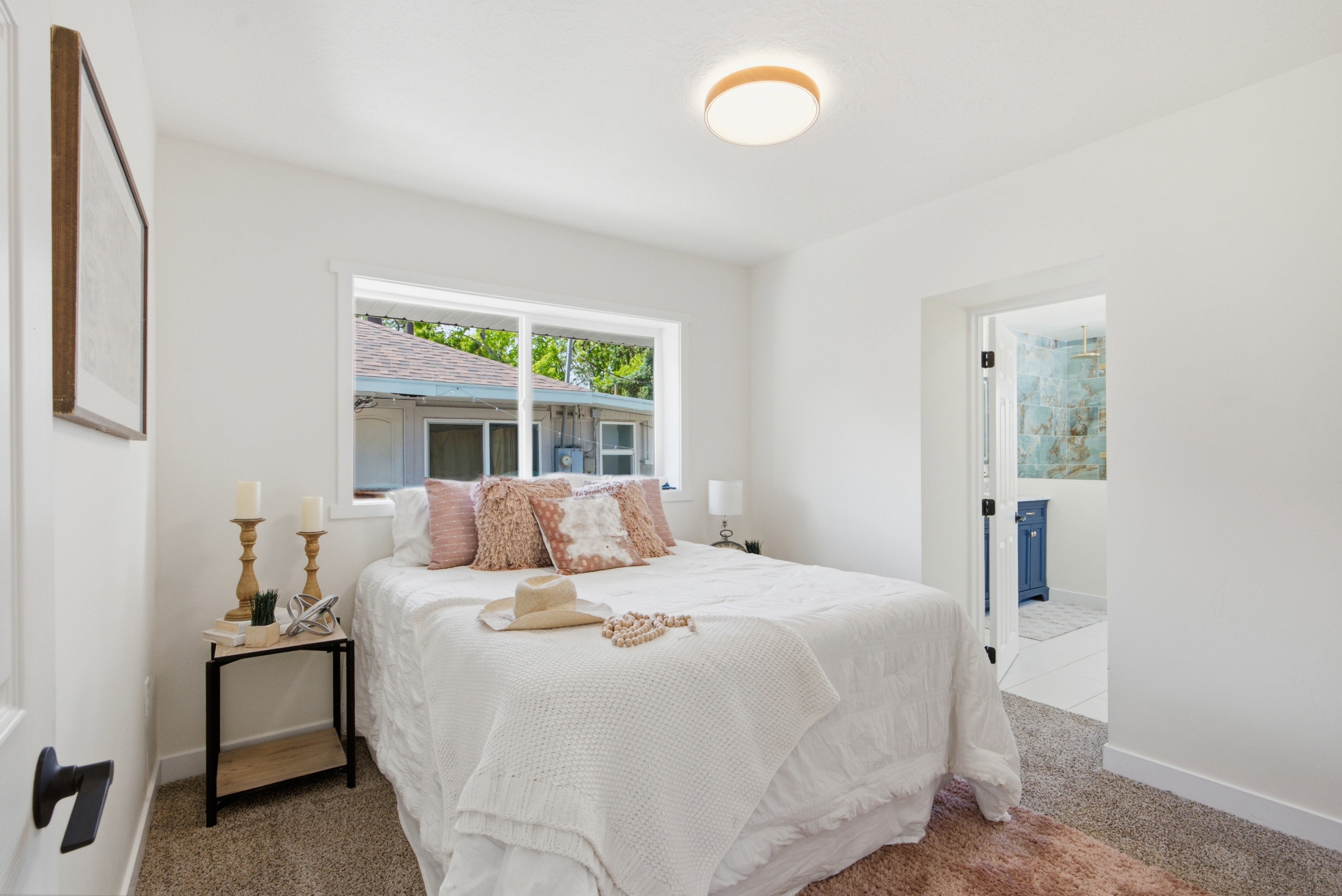 Bedroom featuring a white ceiling and walls, neutral carpet, and a window providing exterior light