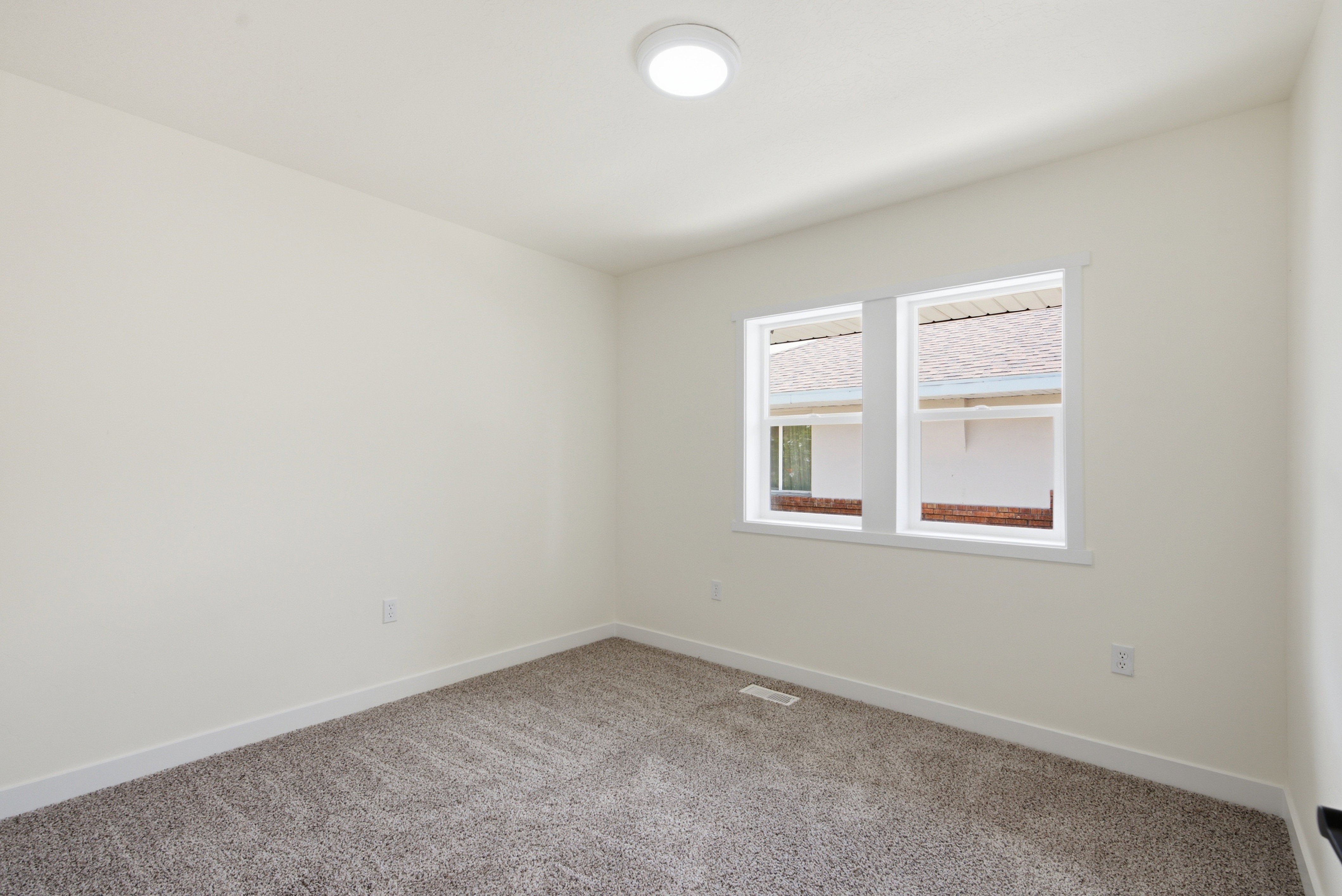 Bright room featuring a flush-mount ceiling light, dual windows with white trim, white wall finishes, and grey carpet flooring