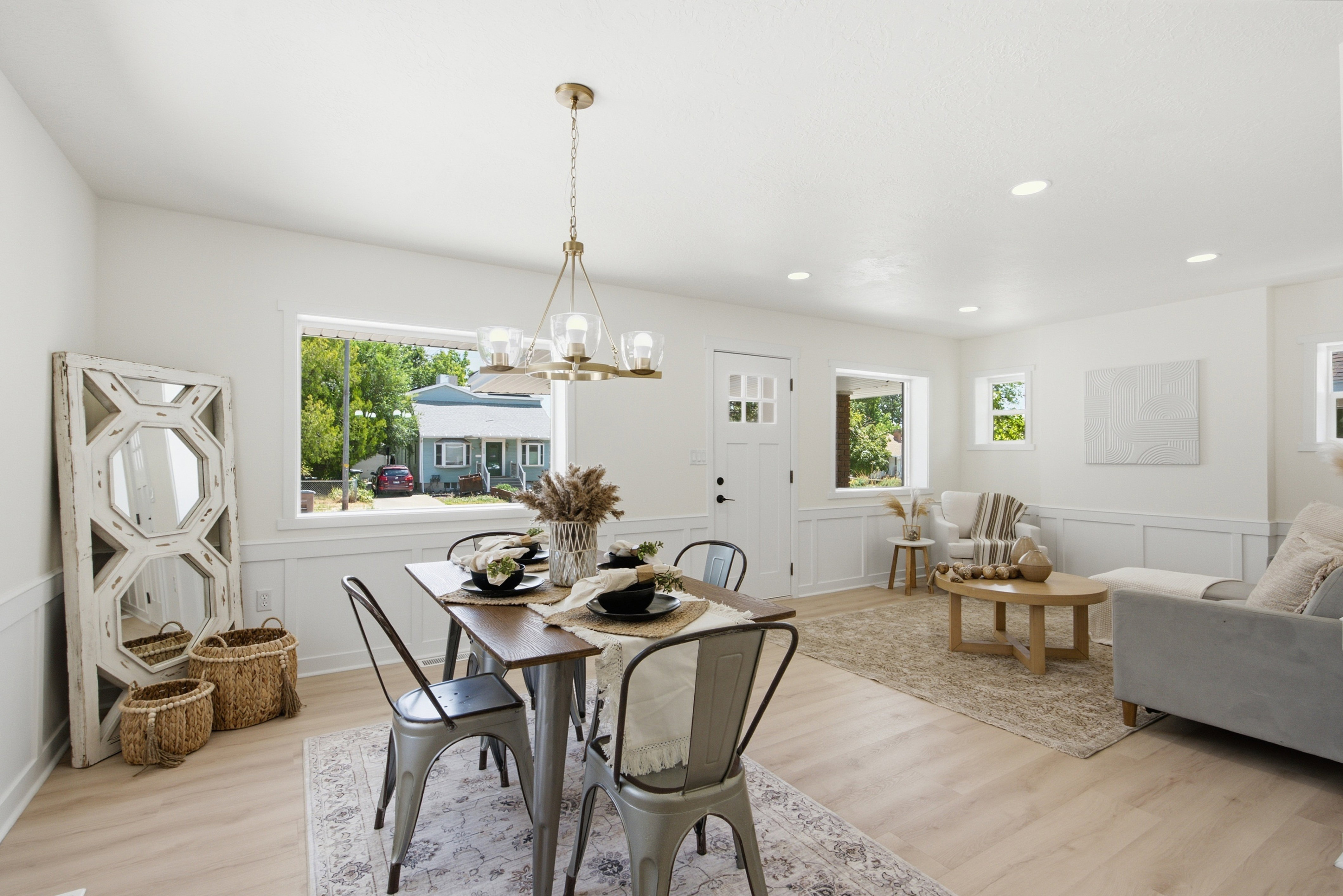 Open concept living and dining area featuring light wood-finish flooring, recessed lighting, white wainscoting, and large windows