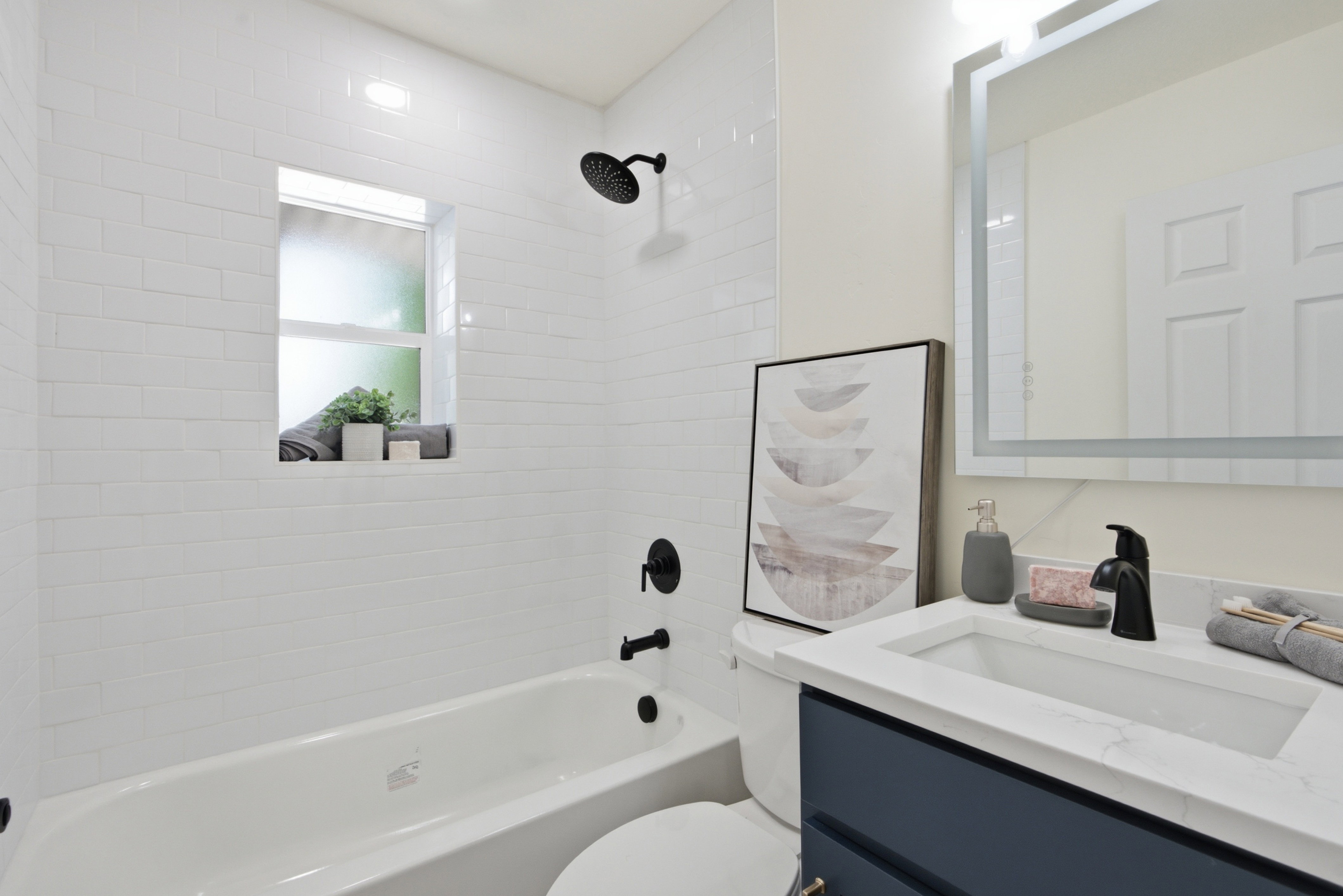 Bathroom featuring a white subway tile shower surround with a built-in window and matte black fixtures