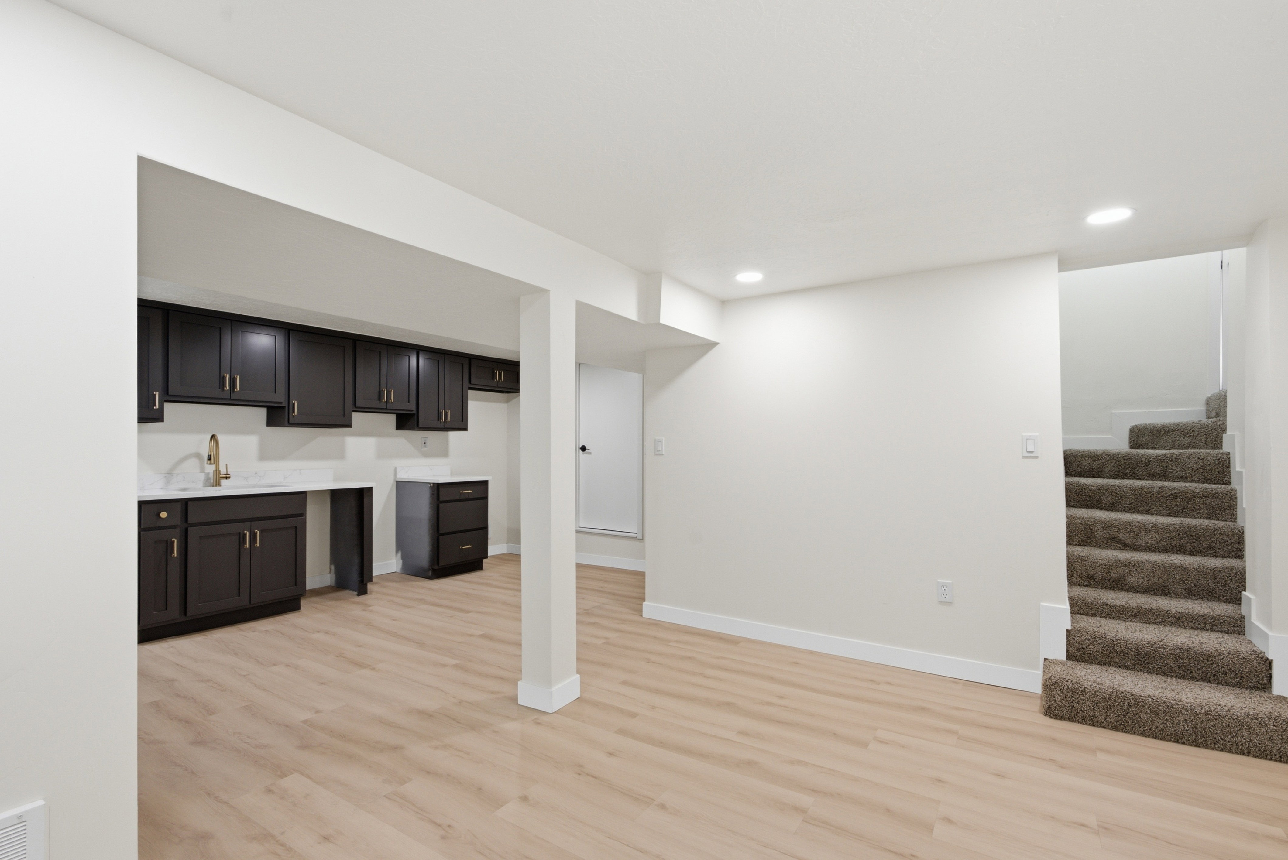 Finished lower level featuring light wood-finish flooring and recessed lighting