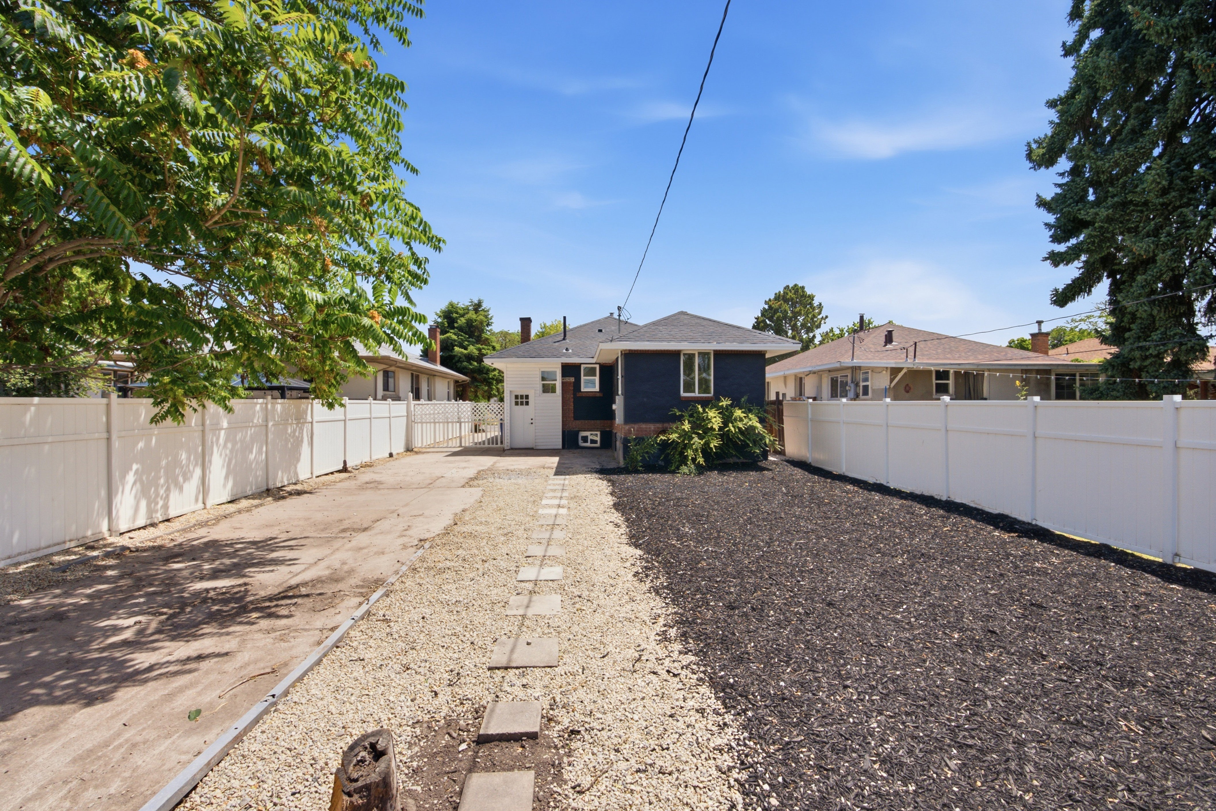 Rear exterior featuring dark siding, white trim, and a white fence