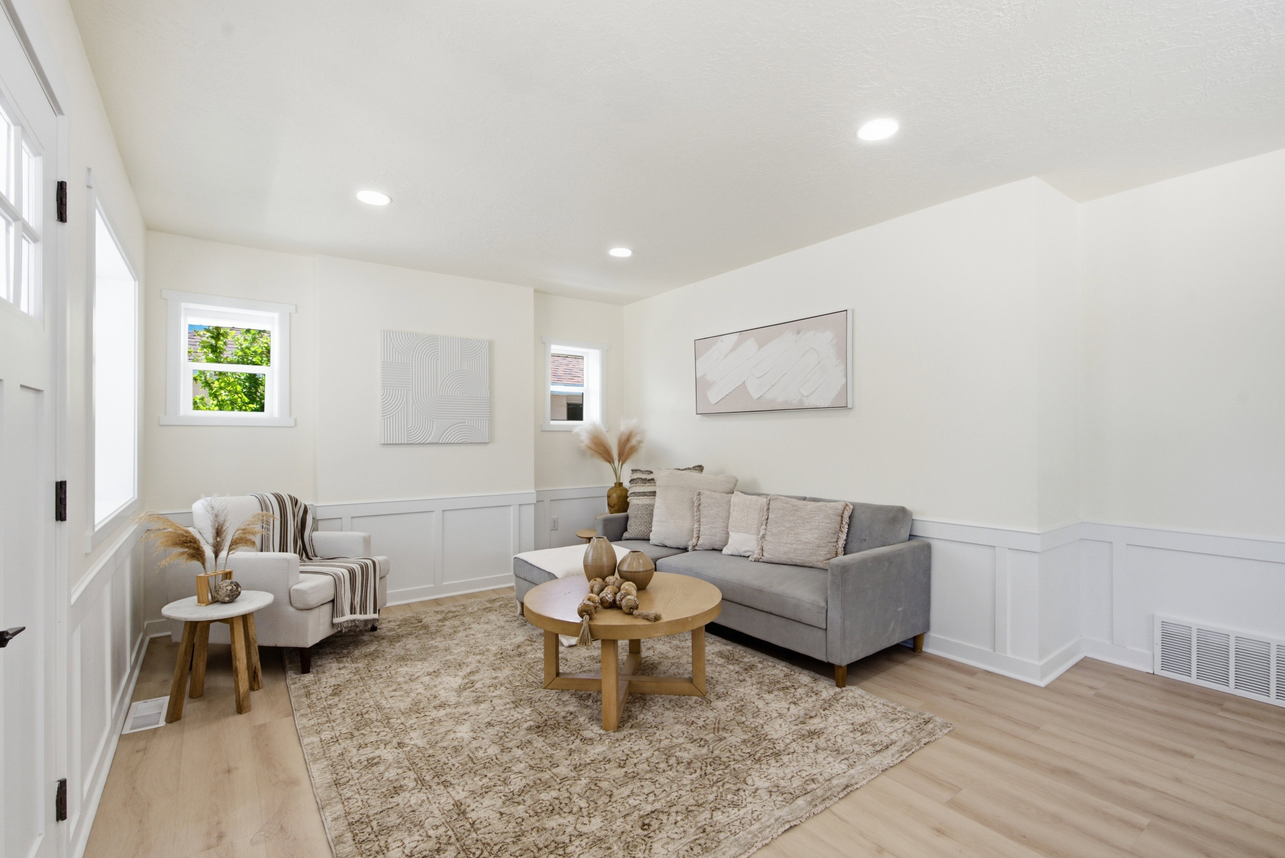 Bright living area featuring wood-finish flooring, recessed lighting, white board and batten wall detailing, and multiple windows
