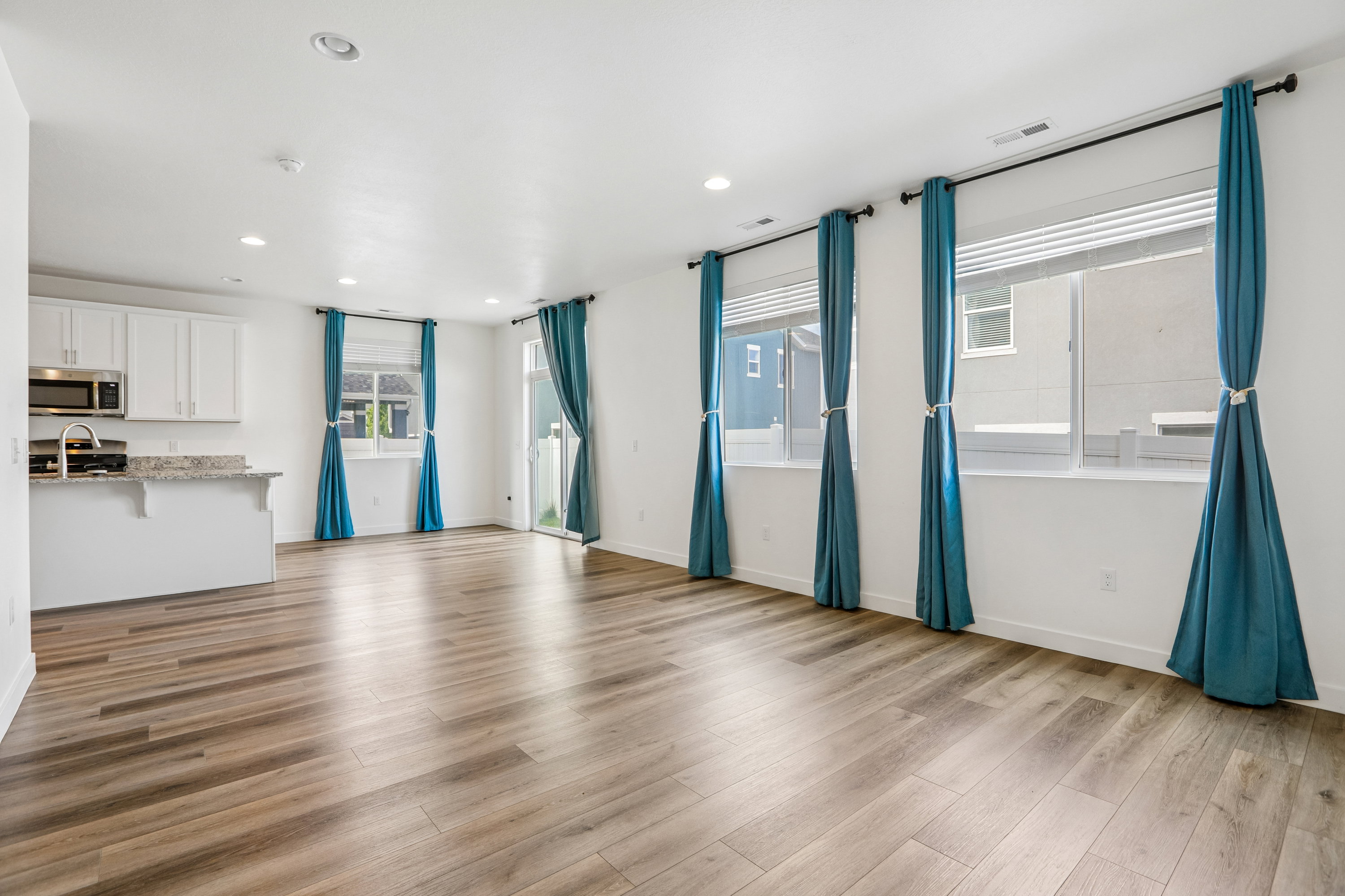 Open-concept living area featuring wood-finish flooring, recessed lighting, and multiple windows