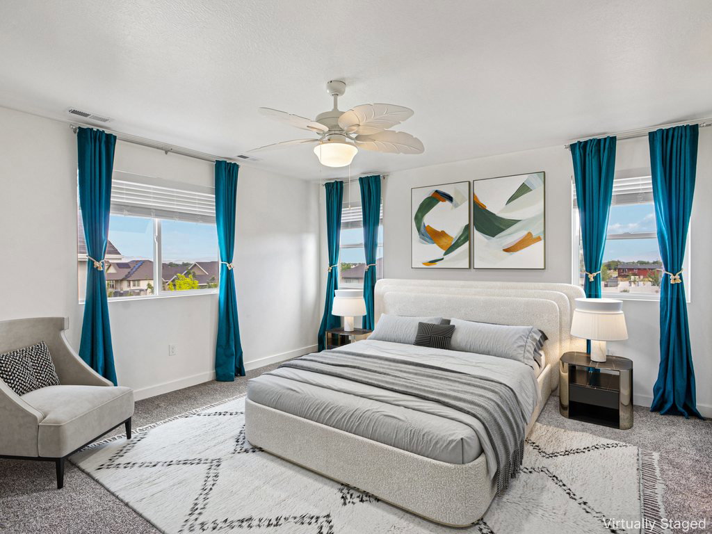 Spacious bedroom featuring multiple windows, a ceiling fan with integrated lighting, and neutral wall paint