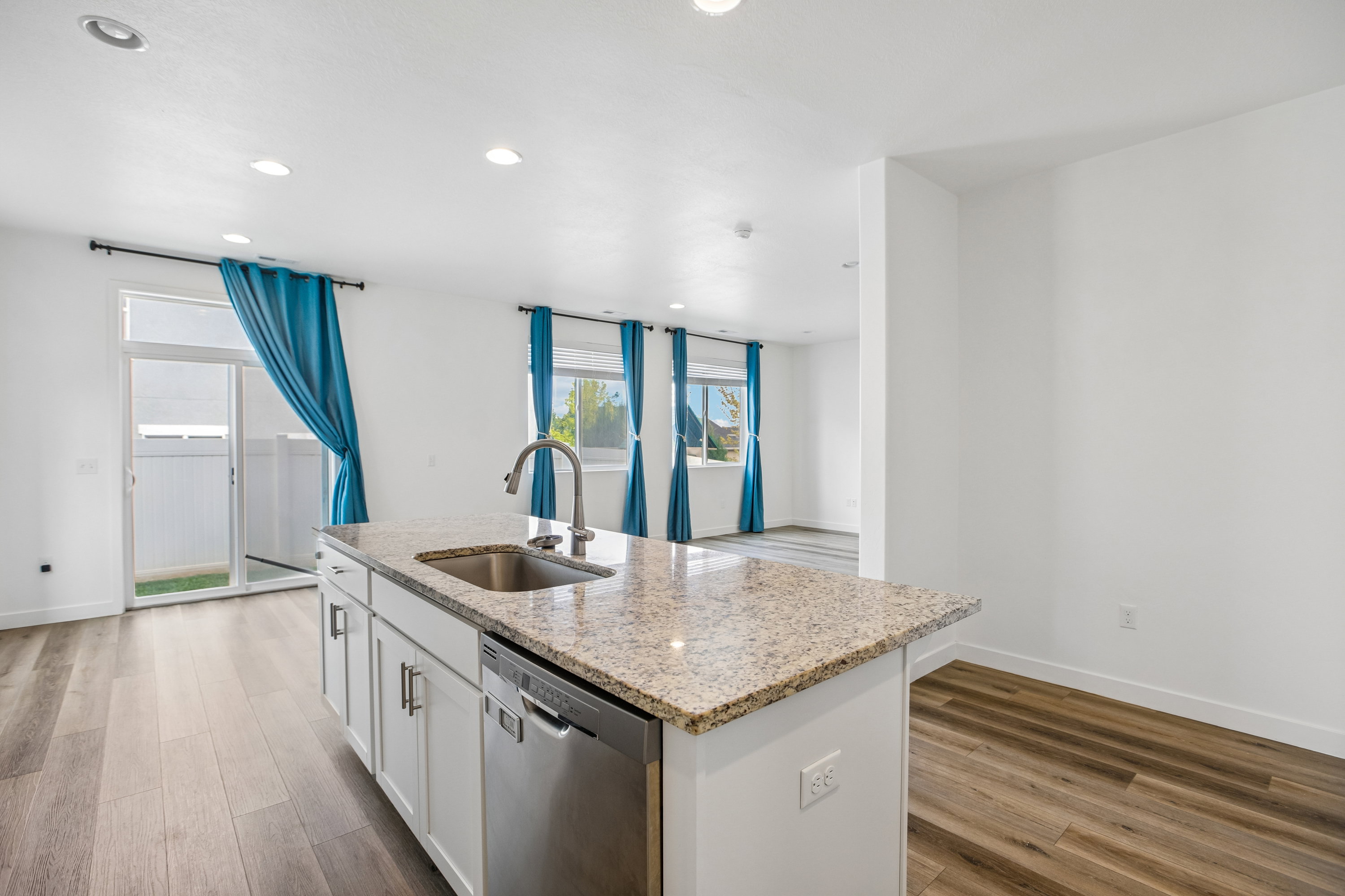 Kitchen island with granite countertop, integrated stainless steel sink, and stainless steel dishwasher