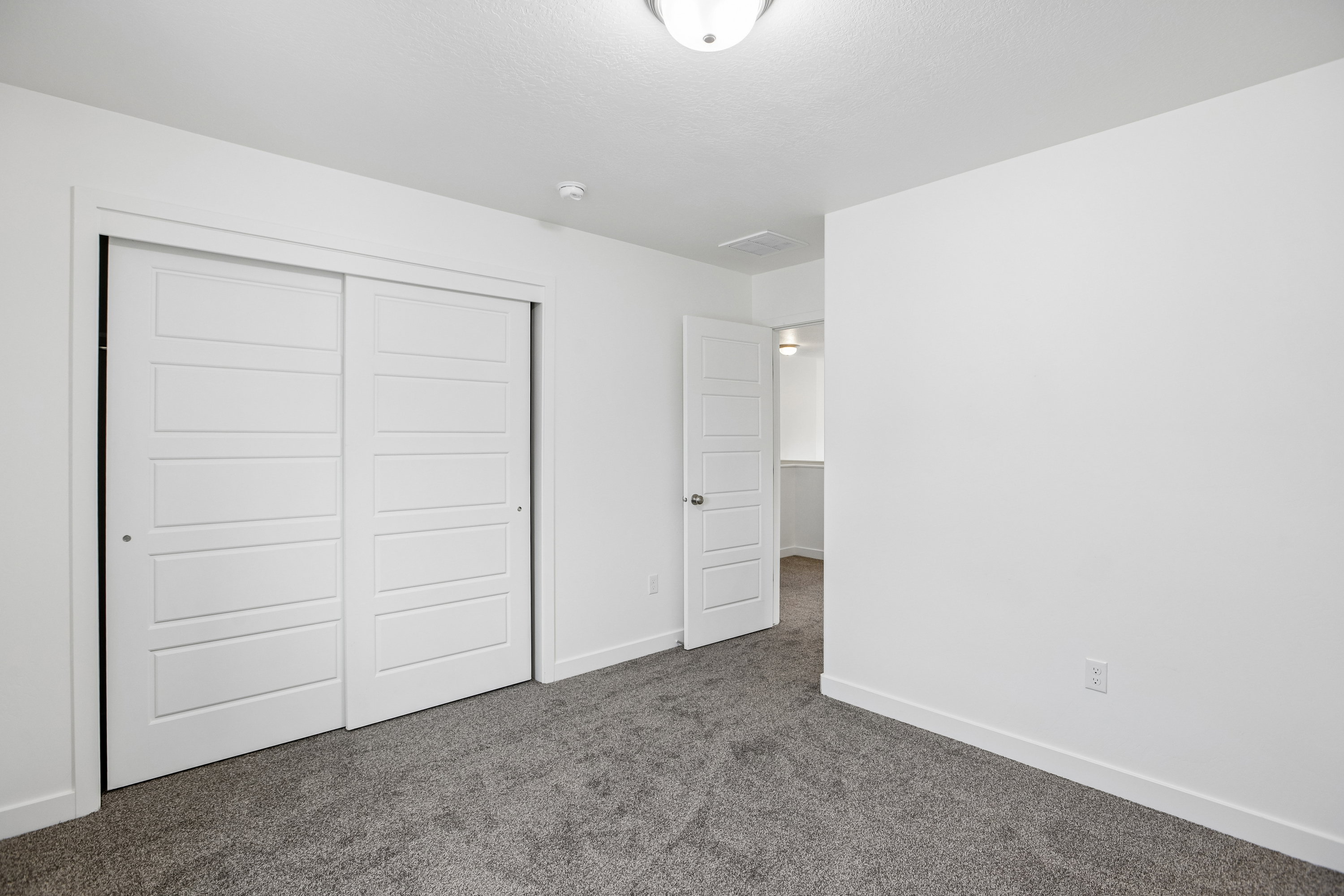 Bedroom featuring sliding closet doors with horizontal paneling, gray carpet flooring, white walls, and a semi-flush ceiling light fixture