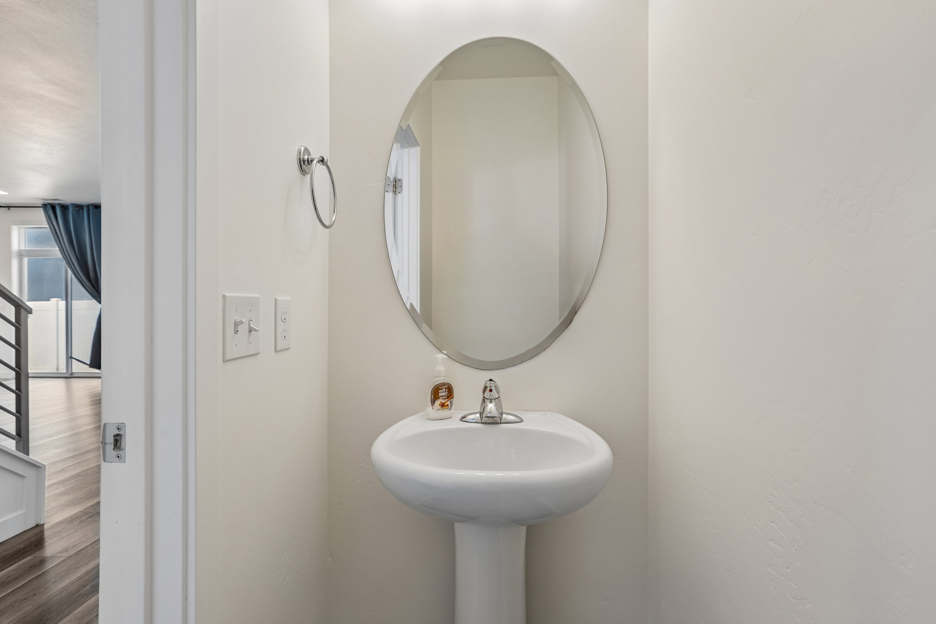 Pedestal sink with a polished chrome faucet and an oval mirror