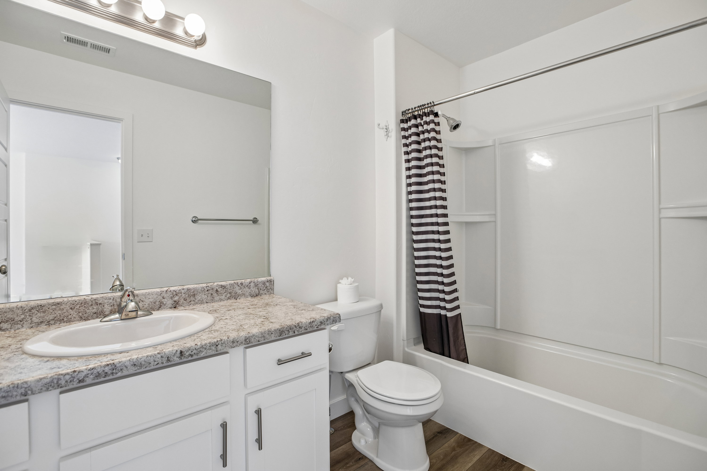 Bathroom featuring a white vanity with a patterned countertop, integral sink, and brushed nickel faucet