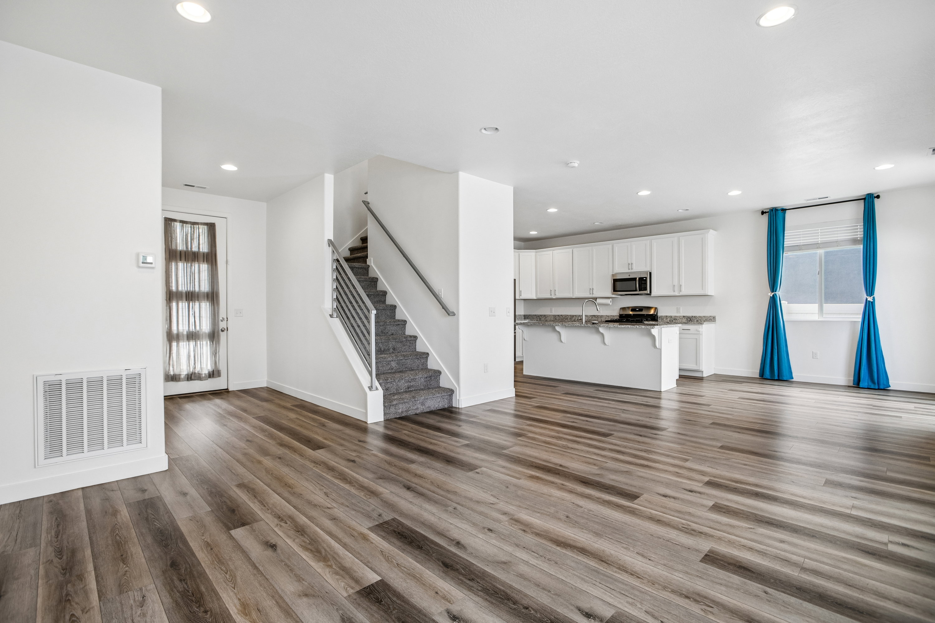 Open-concept living space featuring wood-finish flooring, recessed lighting, and a modern kitchen