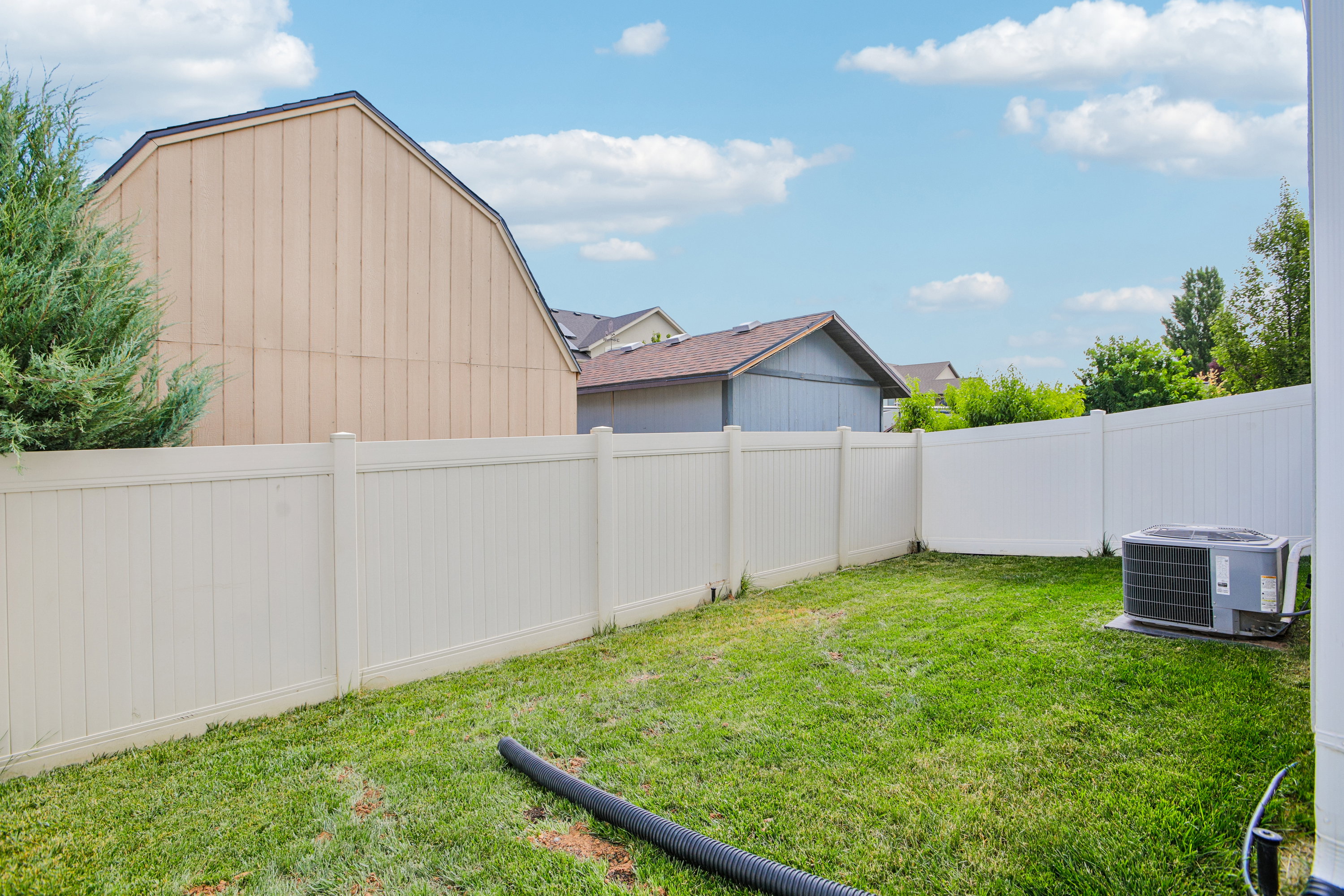 Expansive backyard featuring a manicured lawn, full perimeter fencing, and mature landscaping