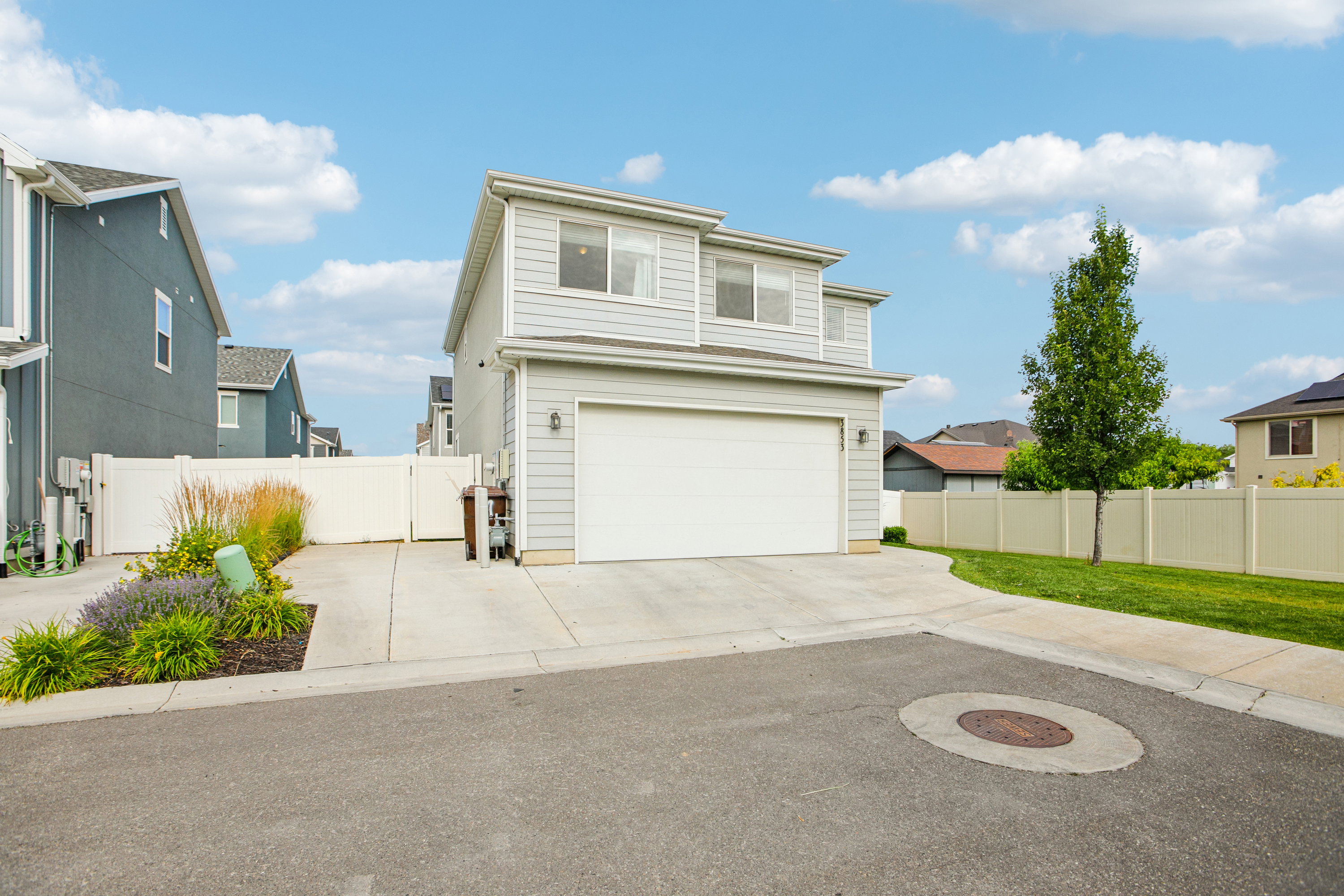 Contemporary two-story residence featuring light gray siding and an attached two-car garage