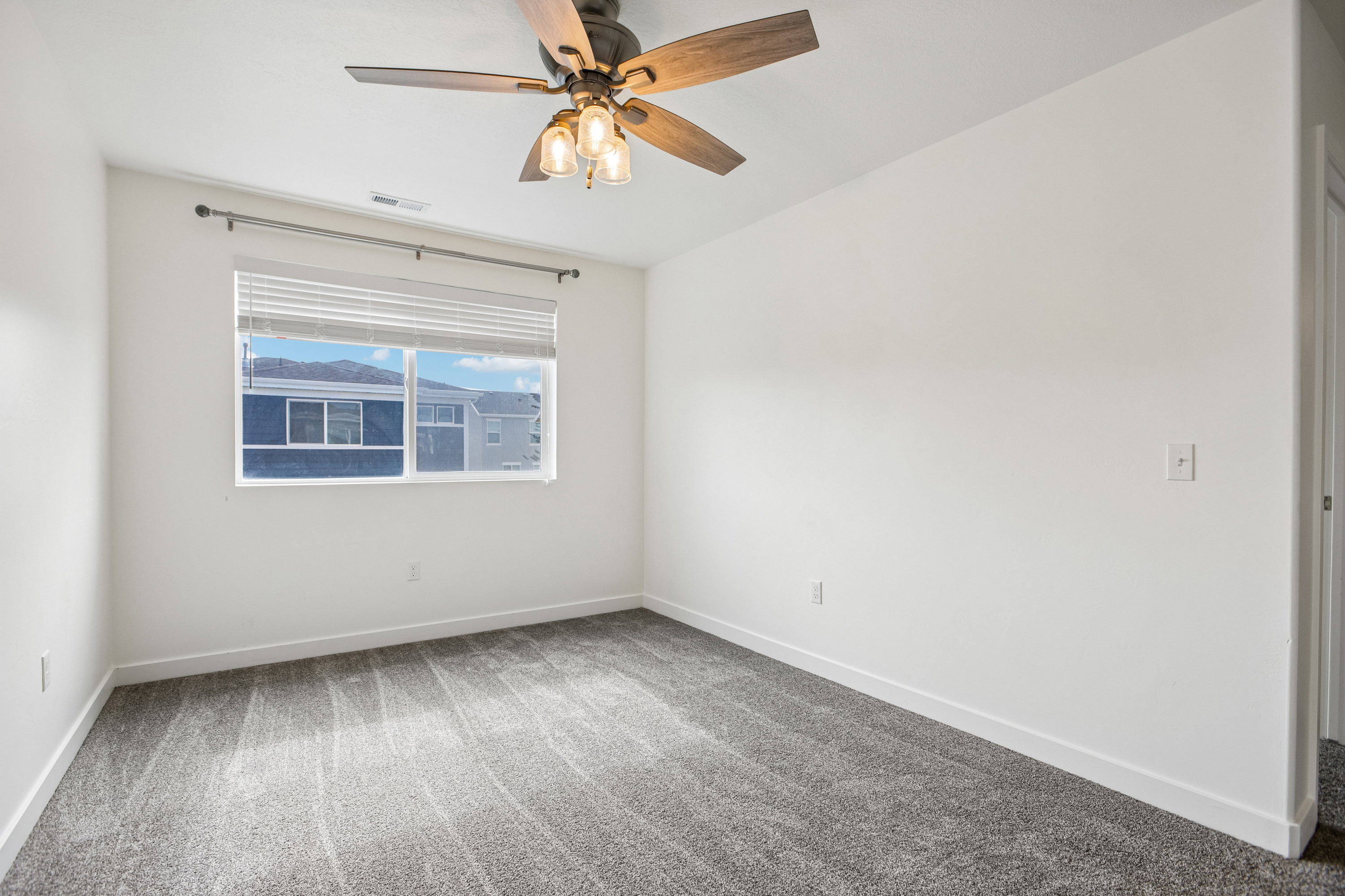 Bedroom featuring a window with integrated blinds, a ceiling fan with integrated lighting, and gray patterned carpet flooring