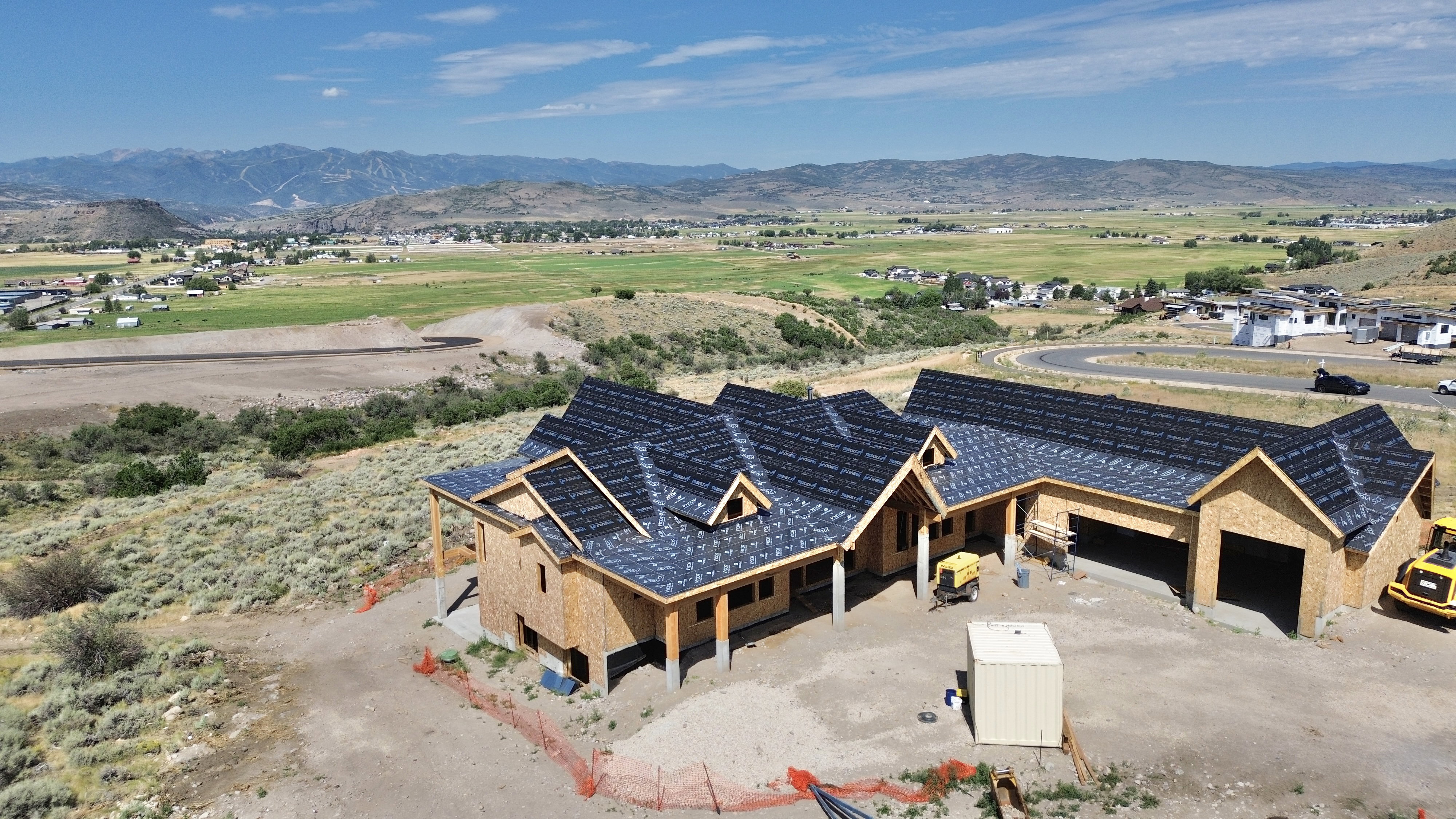 Newly constructed residence showcasing a dark shingled roof and wood-sheathed exterior