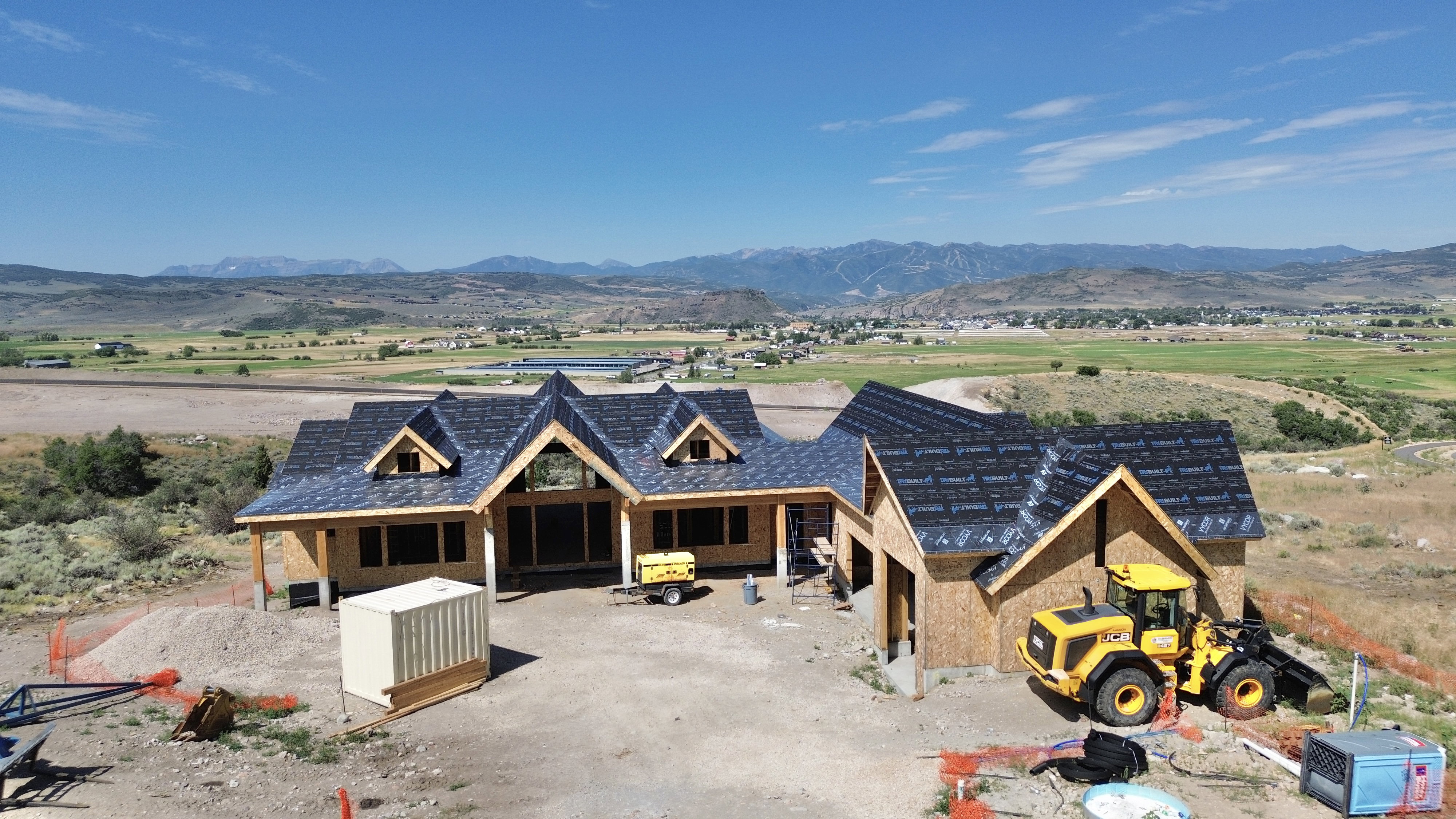 New construction opportunity featuring a multi-gable roofline, exposed wood beams, and a surrounding natural landscape