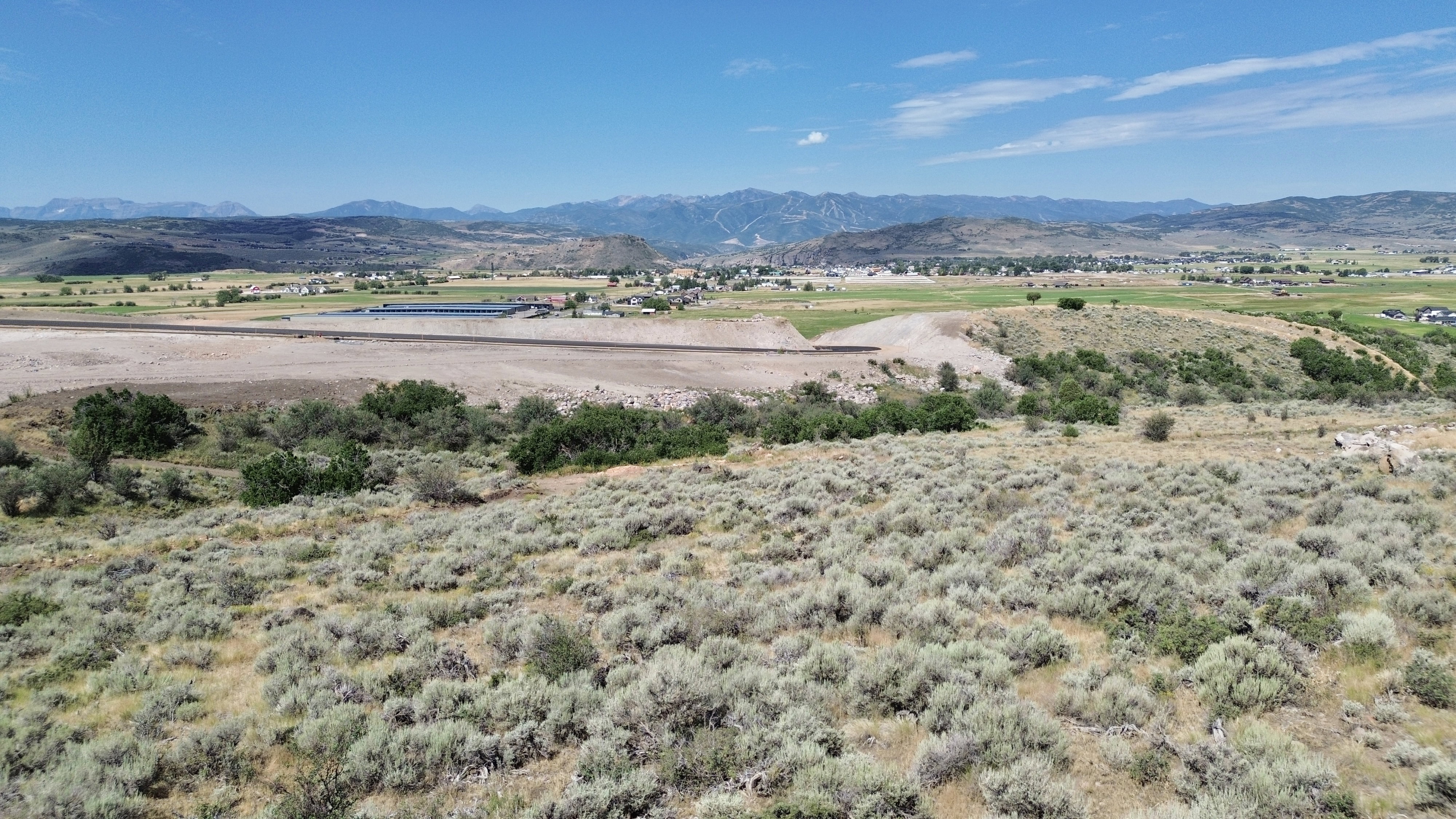 Expansive undeveloped land with natural vegetation and distant mountain ranges under a clear sky