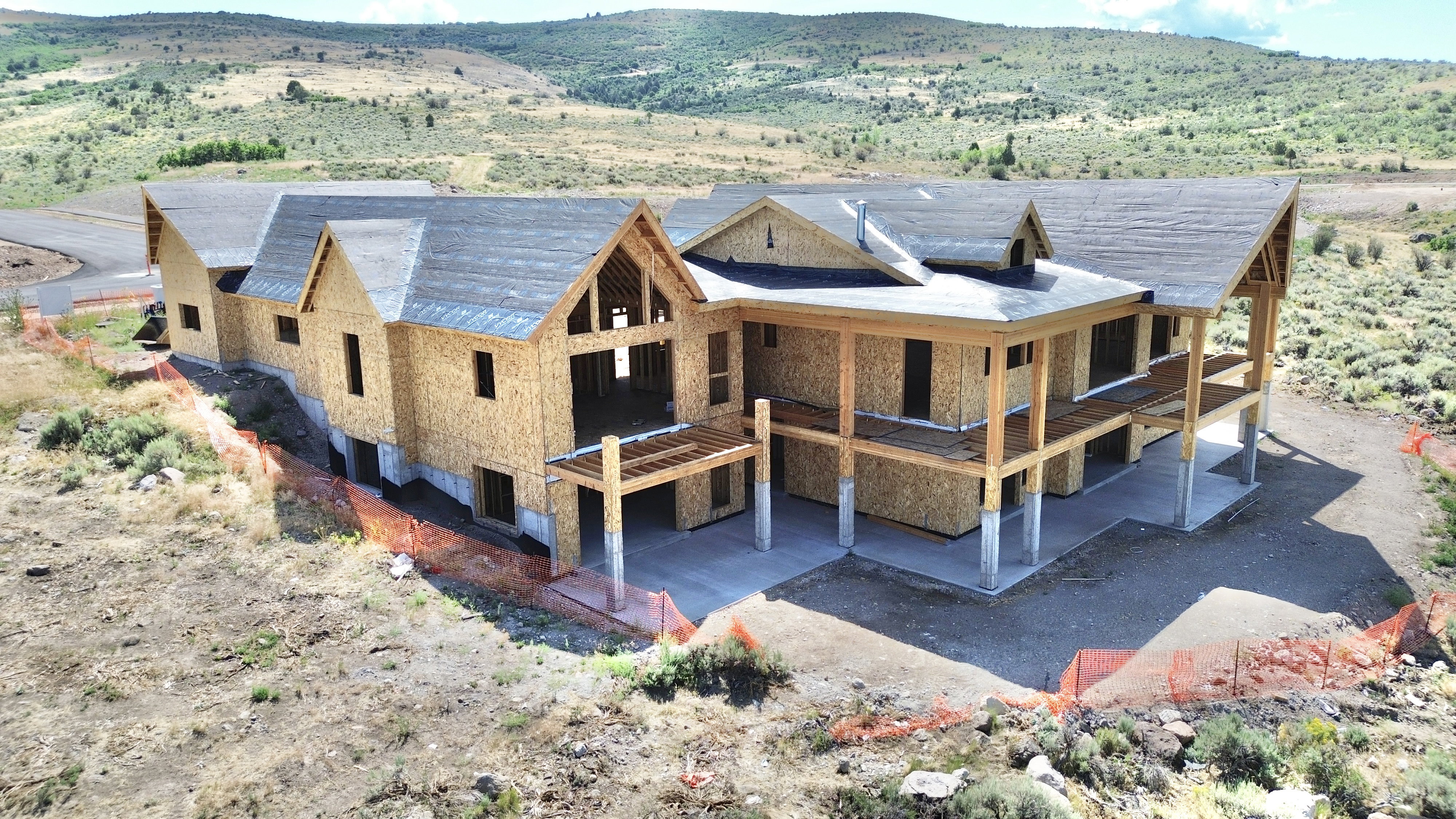 Expansive new construction with multiple gabled rooflines, exposed wood framing, and a tiered concrete patio
