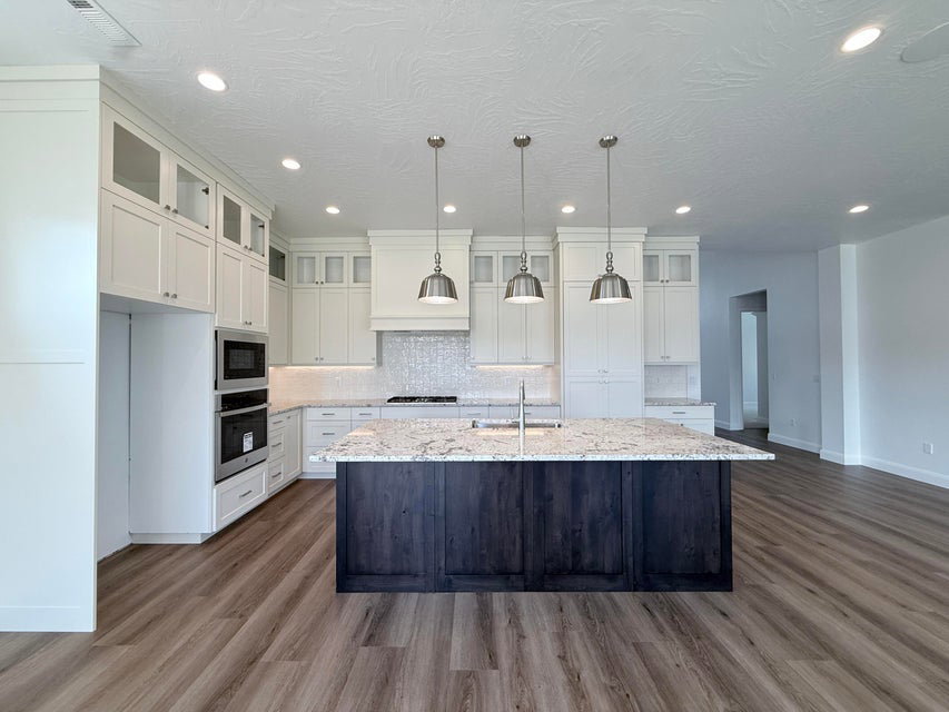 Kitchen featuring a dark wood-finish island with a light-toned countertop, complemented by white cabinetry with glass-front accents