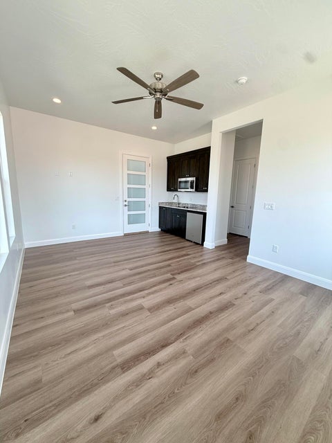 Spacious room featuring wood-finish flooring, a contemporary ceiling fan, and recessed lighting
