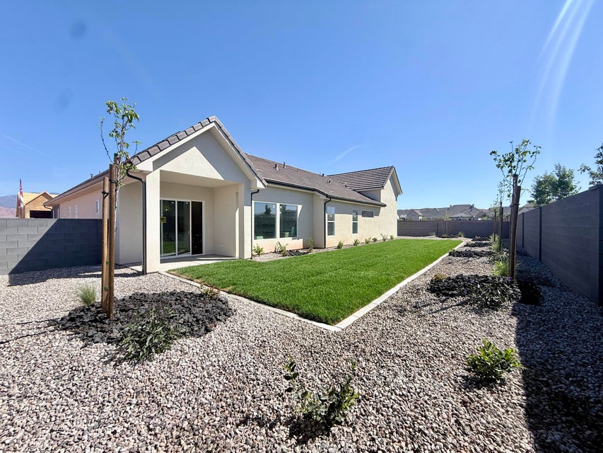 Spacious backyard featuring a manicured lawn area, gravel landscaping, and a privacy fence