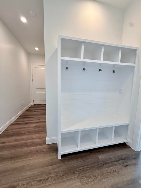 Built-in white storage unit featuring upper cubbies, lower cubbies, and a bench with coat hooks