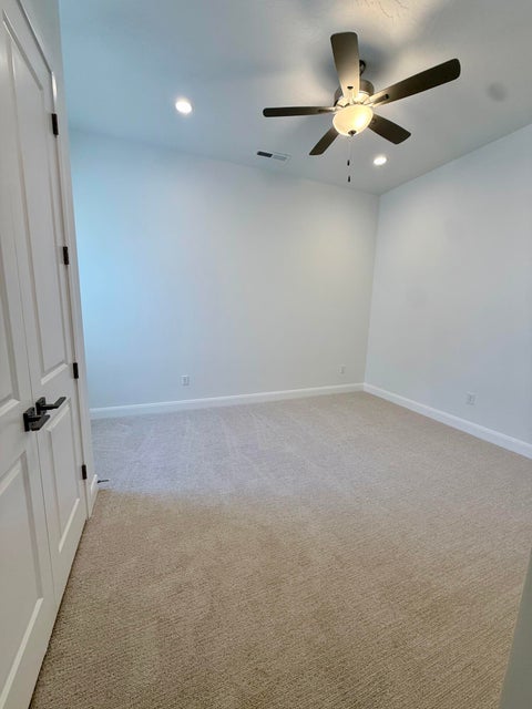 Carpeted interior room featuring a ceiling fan with integrated lighting, recessed ceiling lights, white walls, and white baseboards