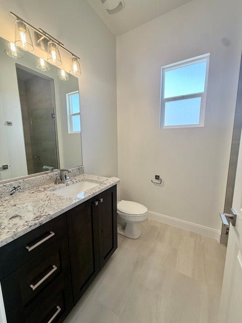 Bathroom featuring a dark wood-finish vanity with a light-toned countertop, an undermount sink, and contemporary brushed nickel hardware