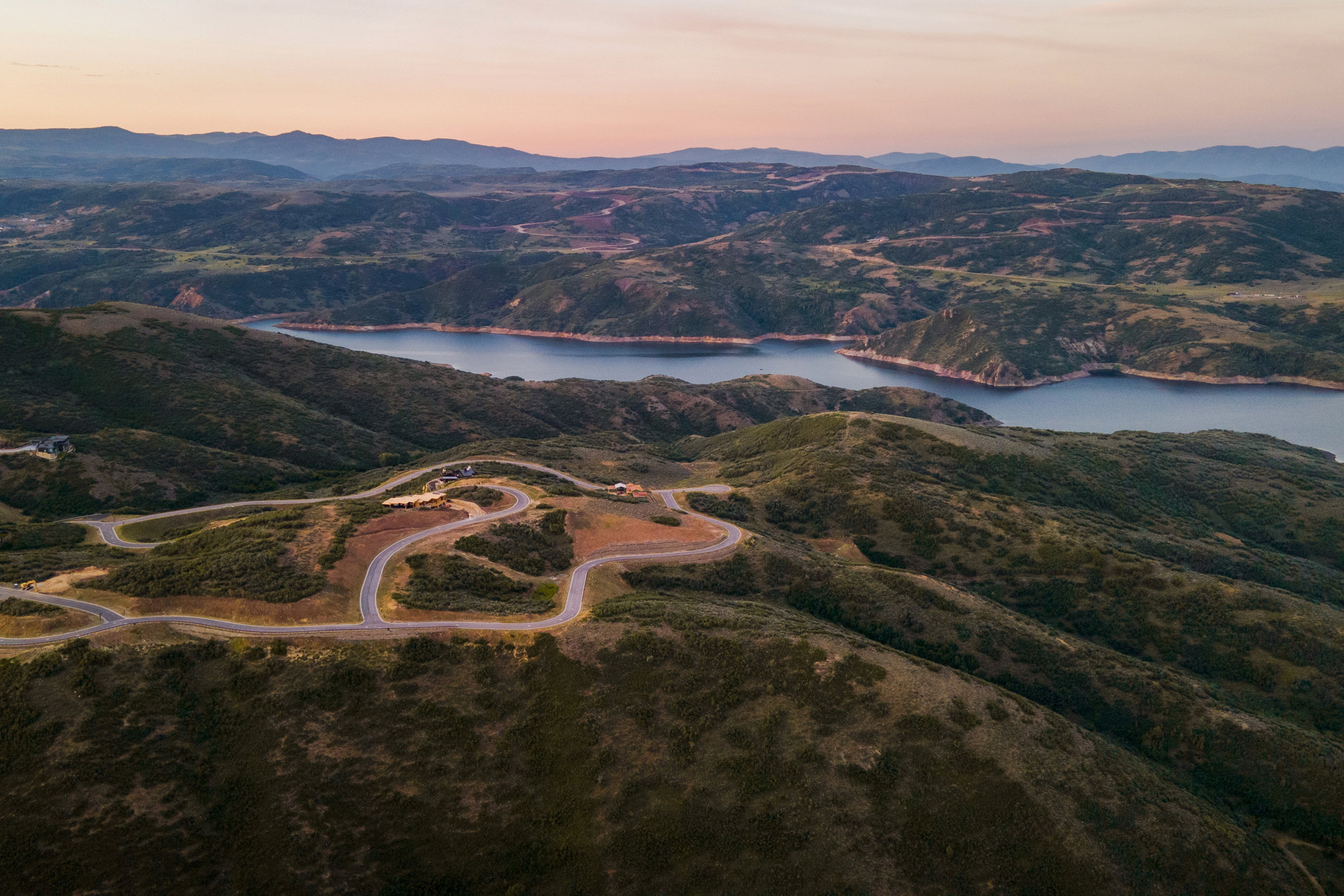 Expansive mountain landscape featuring a large body of water, meandering roads, and multiple building sites
