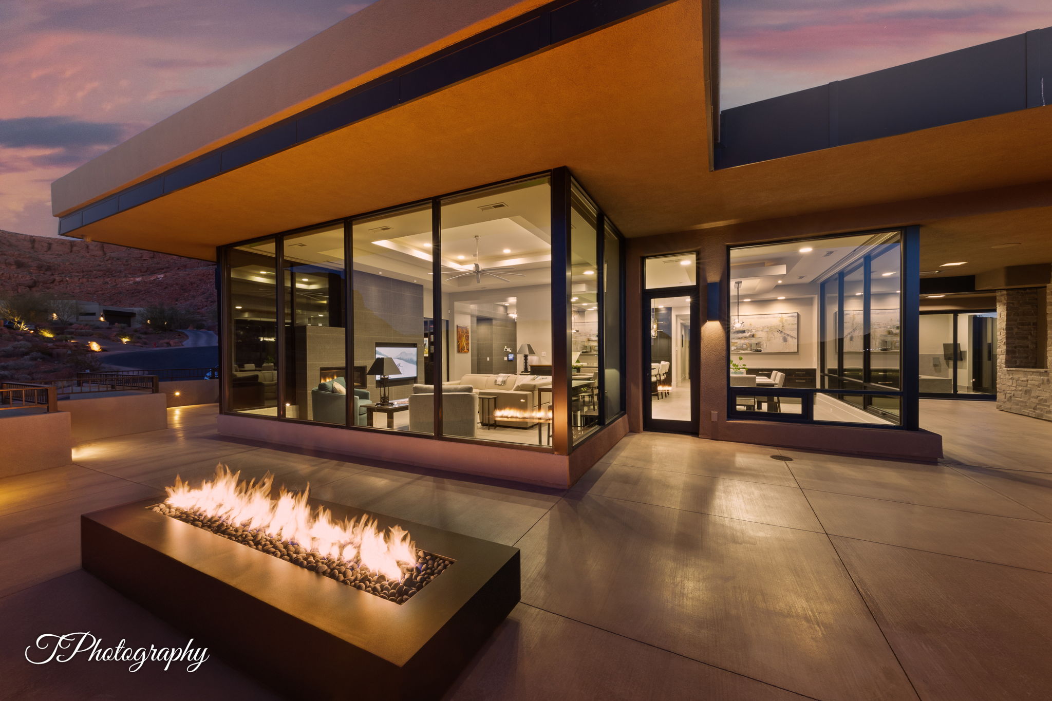 Modern exterior featuring a built-in fire pit, expansive concrete patio, and large glass windows