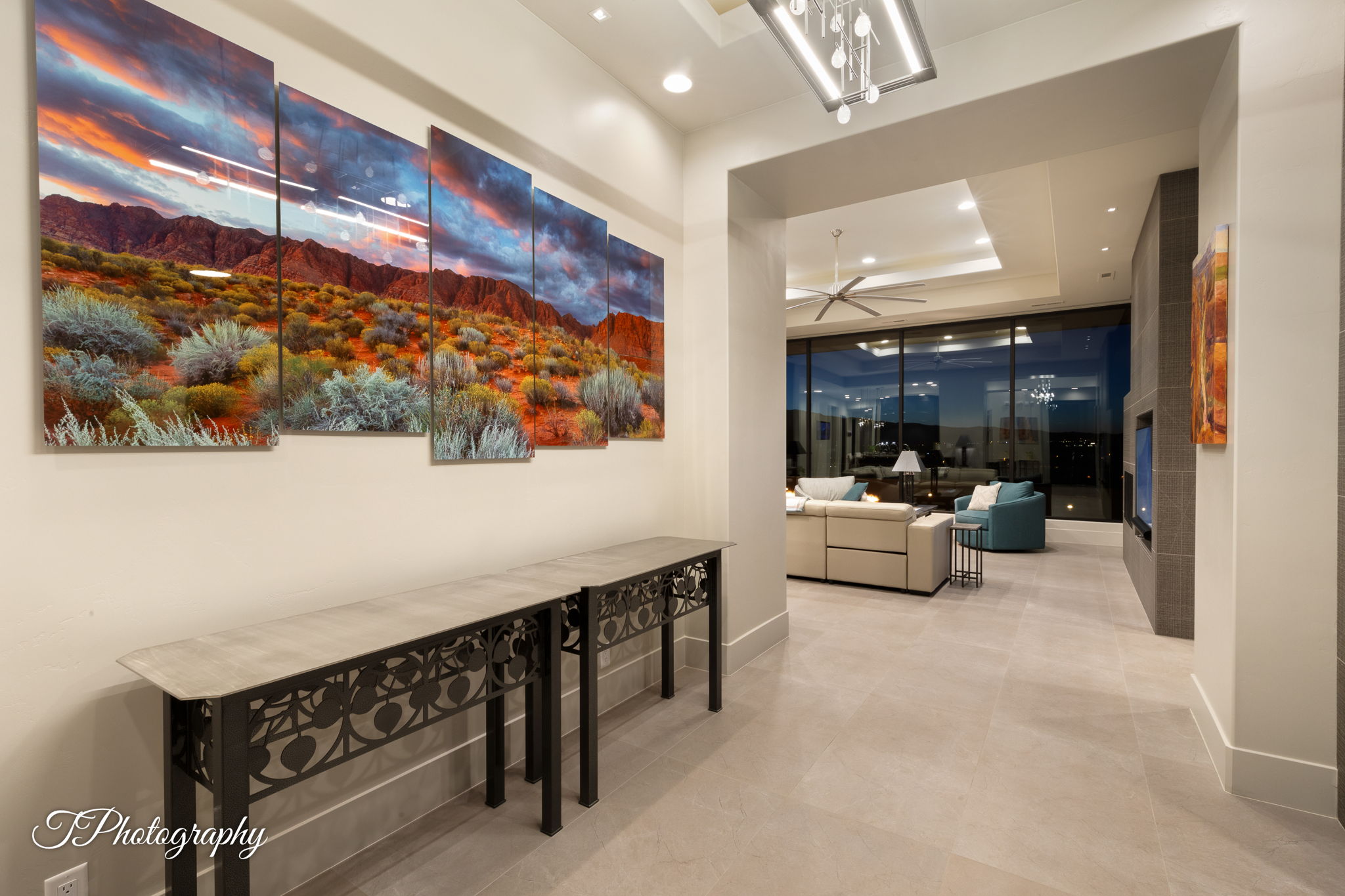 Recessed lighting illuminates a wide hallway with light-colored tile flooring, leading into an expansive living area