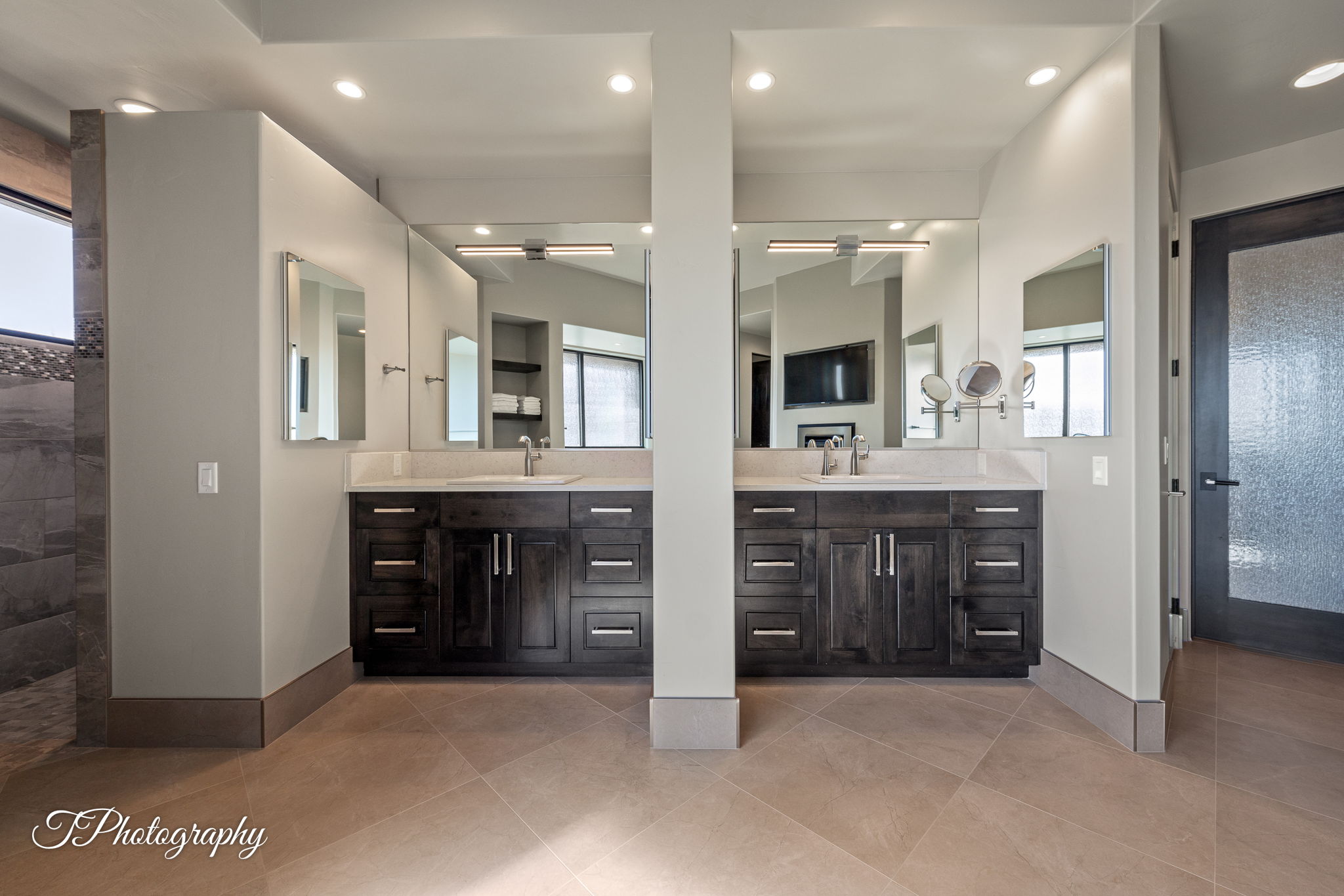 Dual vanity bathroom featuring dark wood cabinetry, light countertops, and large wall-mounted mirrors