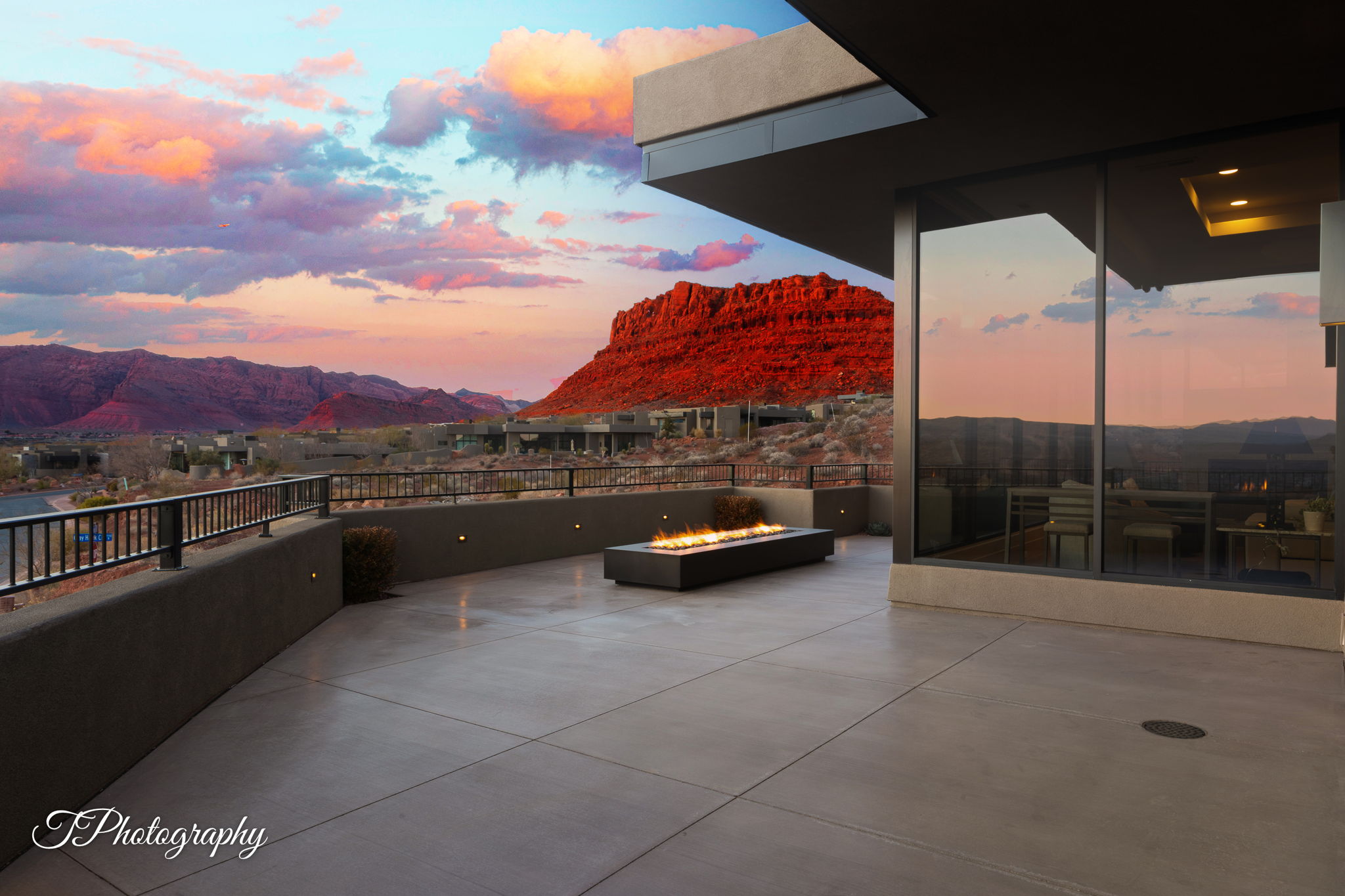 Expansive outdoor terrace featuring a built-in linear fire pit, large format windows, and a metal railing