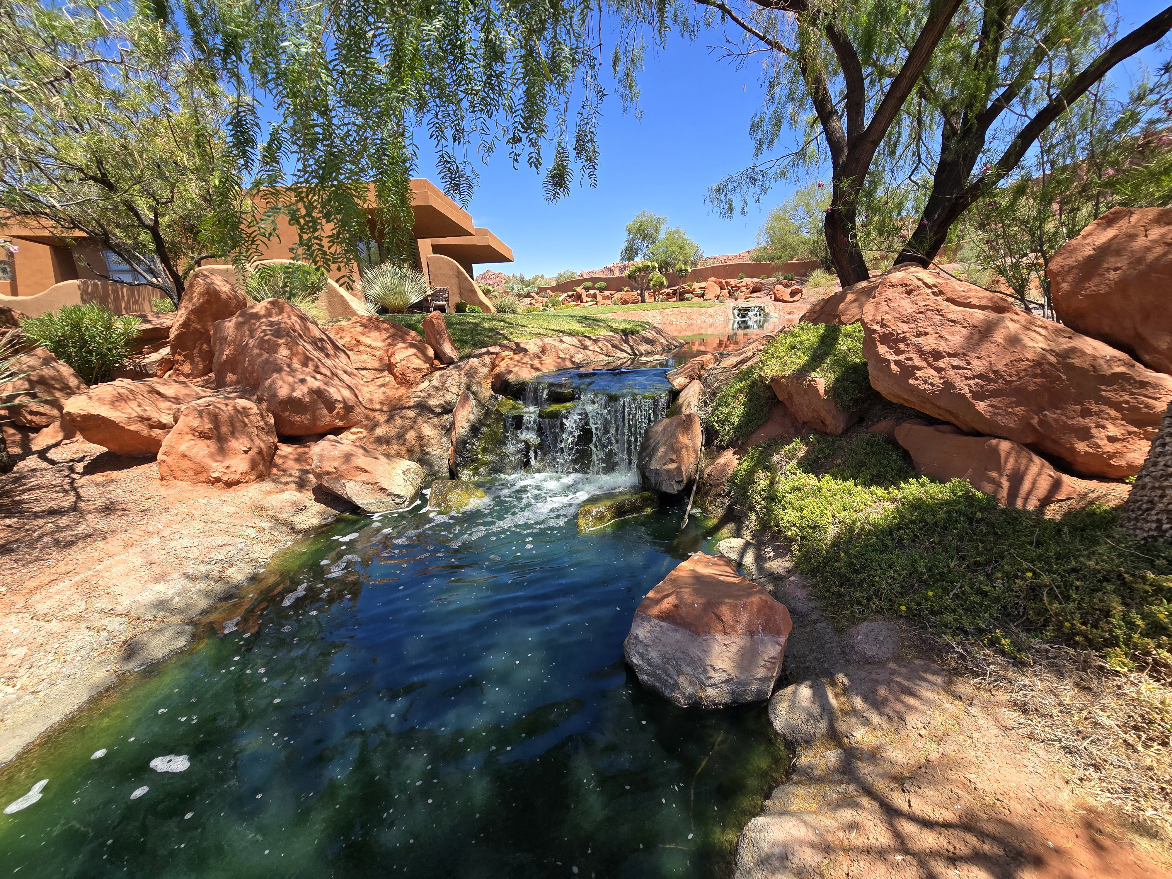 Water feature with a cascading waterfall, surrounded by natural rock formations and desert-adapted landscaping