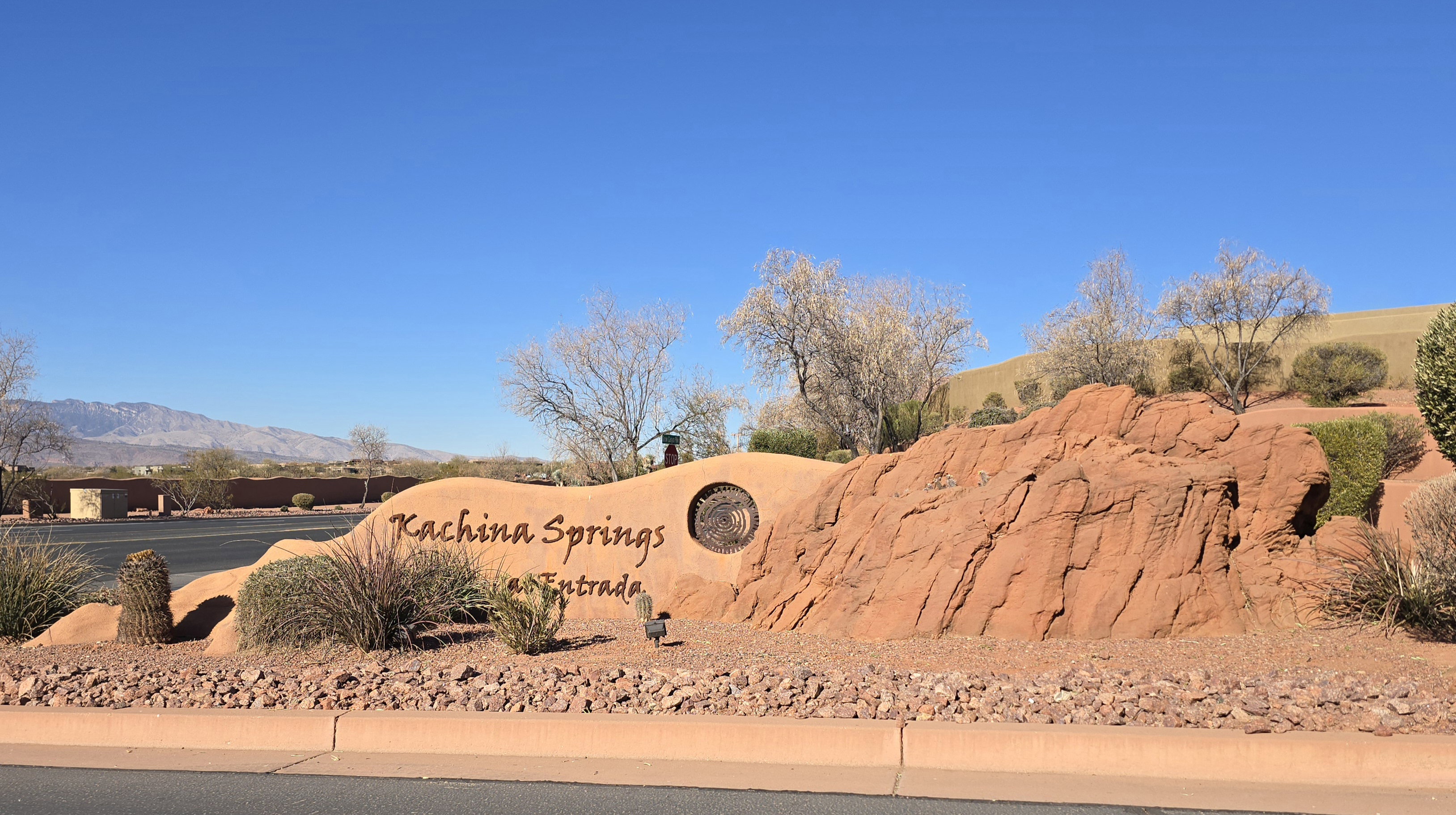 Entry monument featuring "Kachina Springs at Entrada" signage, desert landscaping, red rock formations, and mountain backdrop