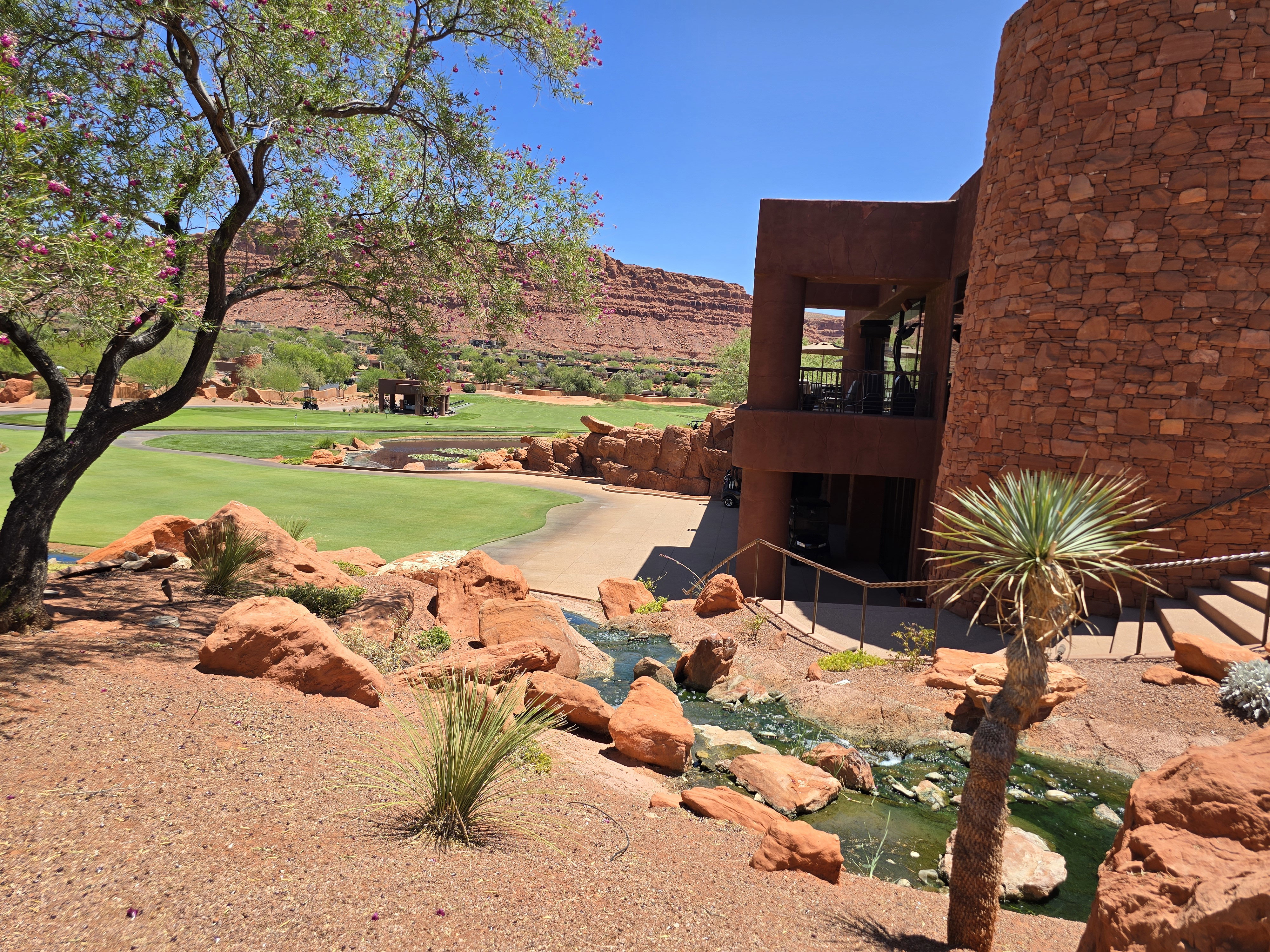 Golf course views from a multi-story structure featuring a stone facade and a private balcony