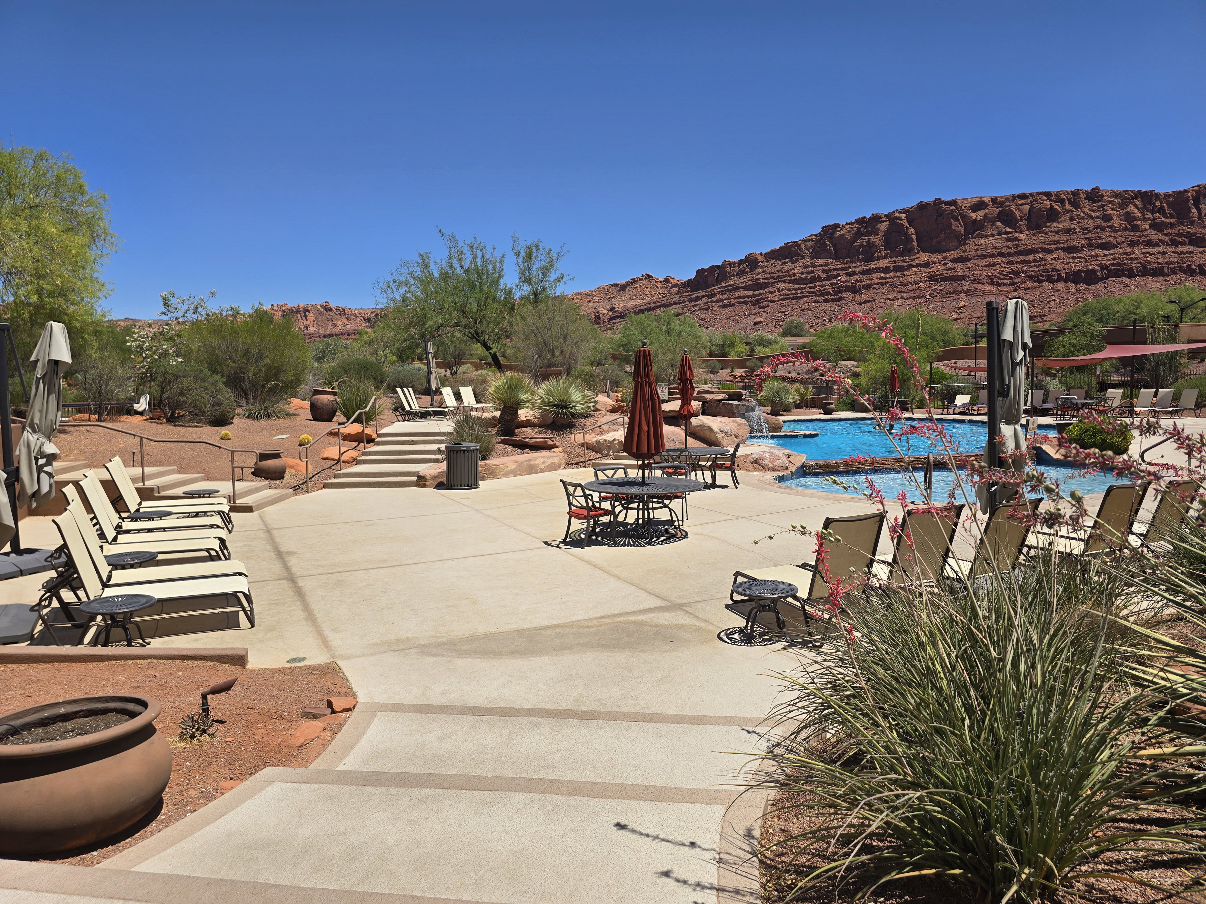 Expansive concrete patio area with a built-in pool featuring a rock waterfall