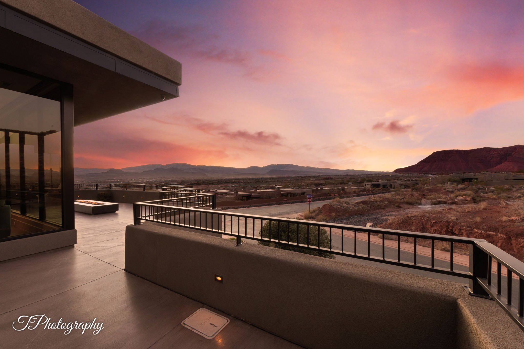Expansive outdoor patio featuring a built-in fire pit, concrete flooring, and durable metal railings