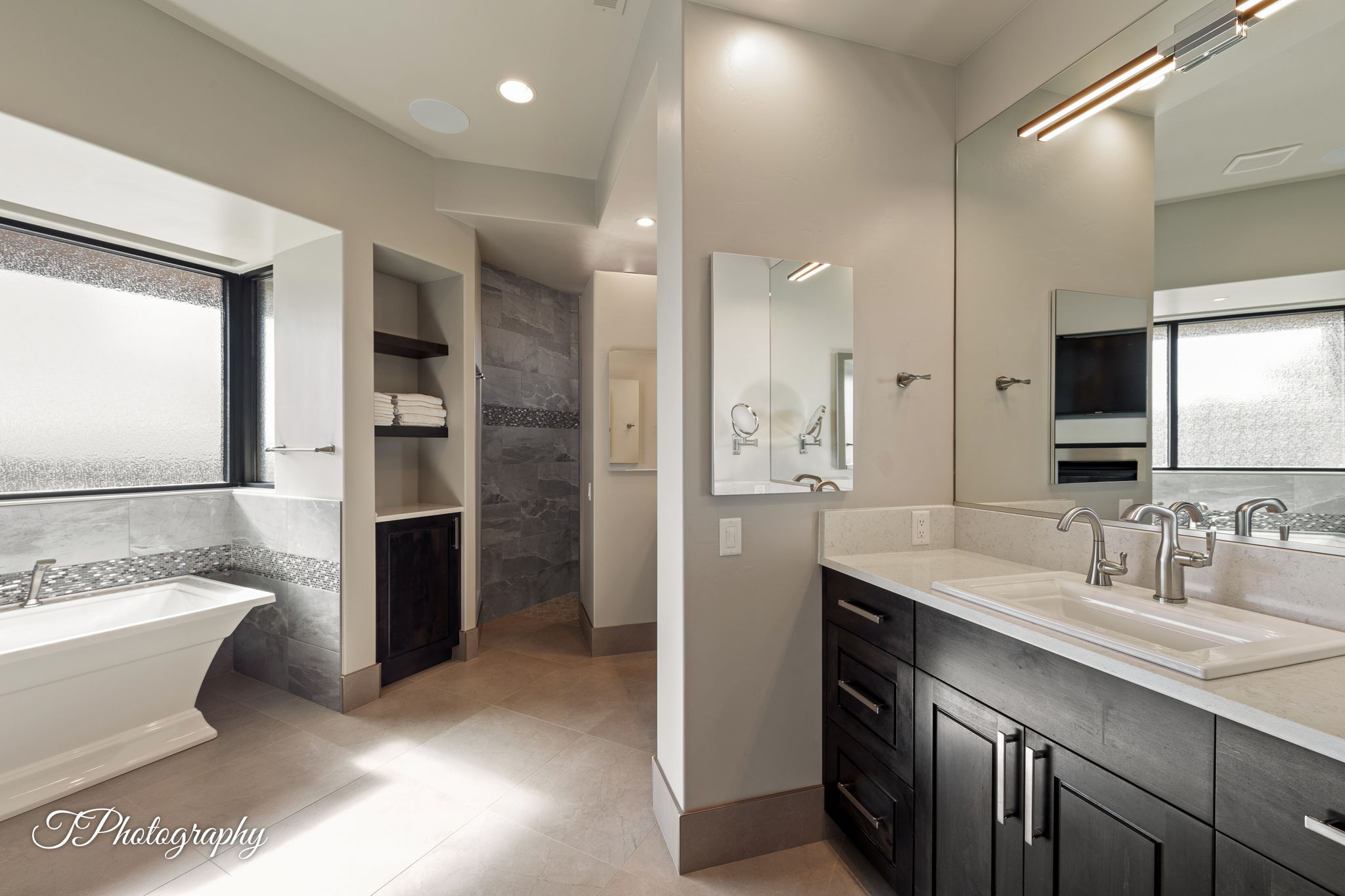 Bathroom featuring a freestanding tub, dual vanity with undermount sinks, and a walk-in shower with stone-look tile
