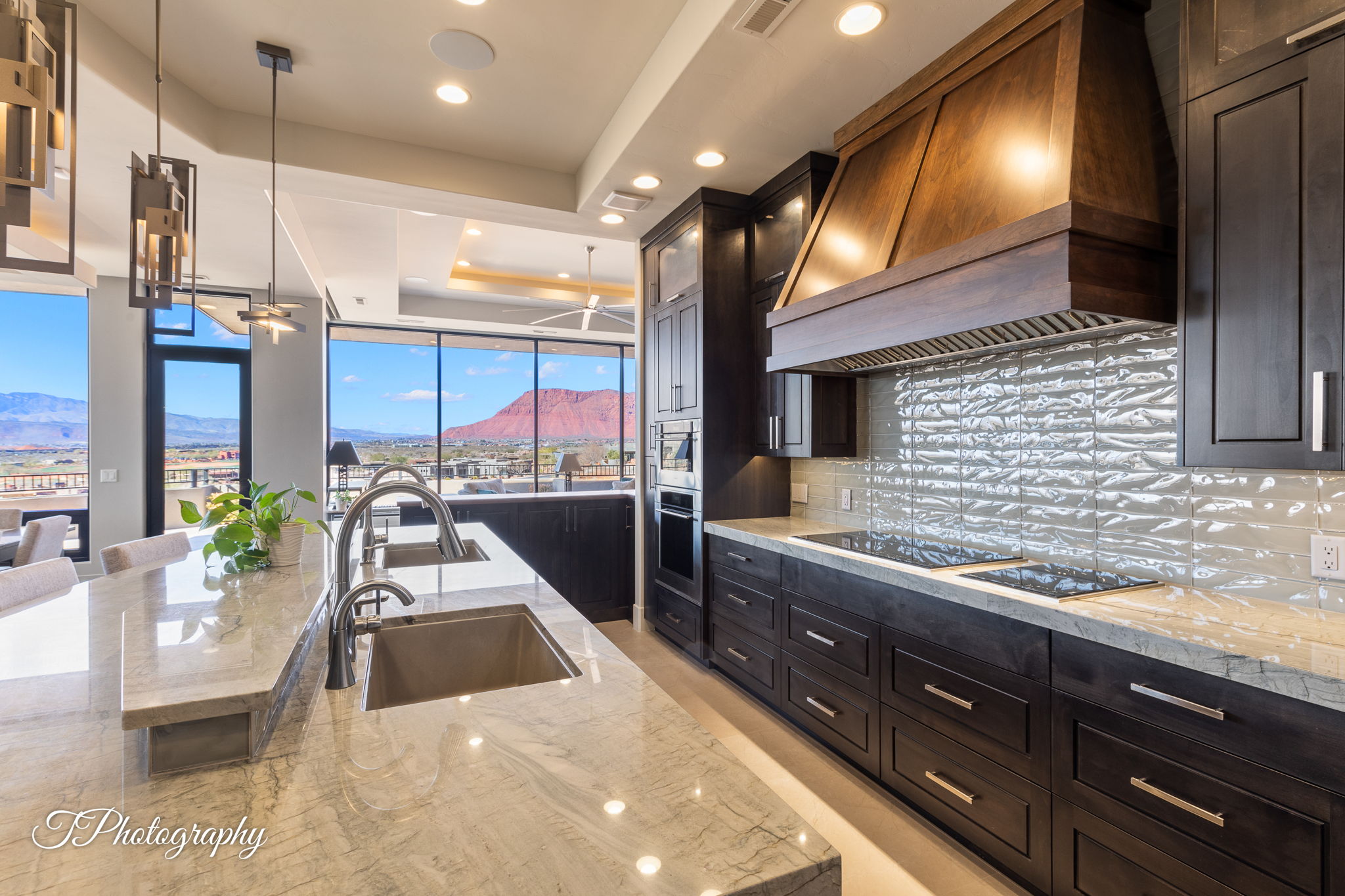 Kitchen featuring a large island with dual sinks, light-toned countertops, and dark wood cabinetry