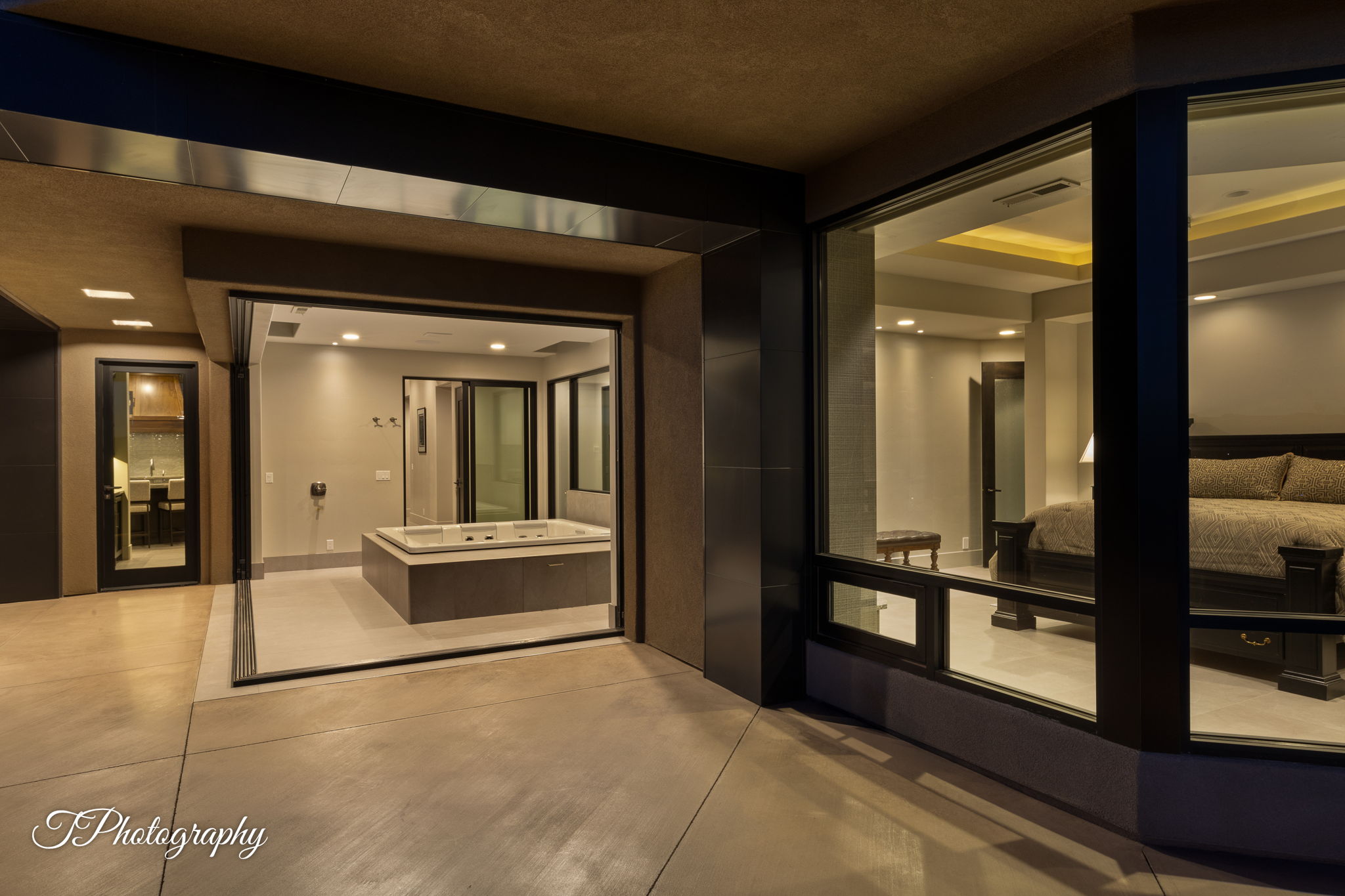 Exterior patio with a built-in spa, large sliding glass doors, and expansive floor-to-ceiling windows