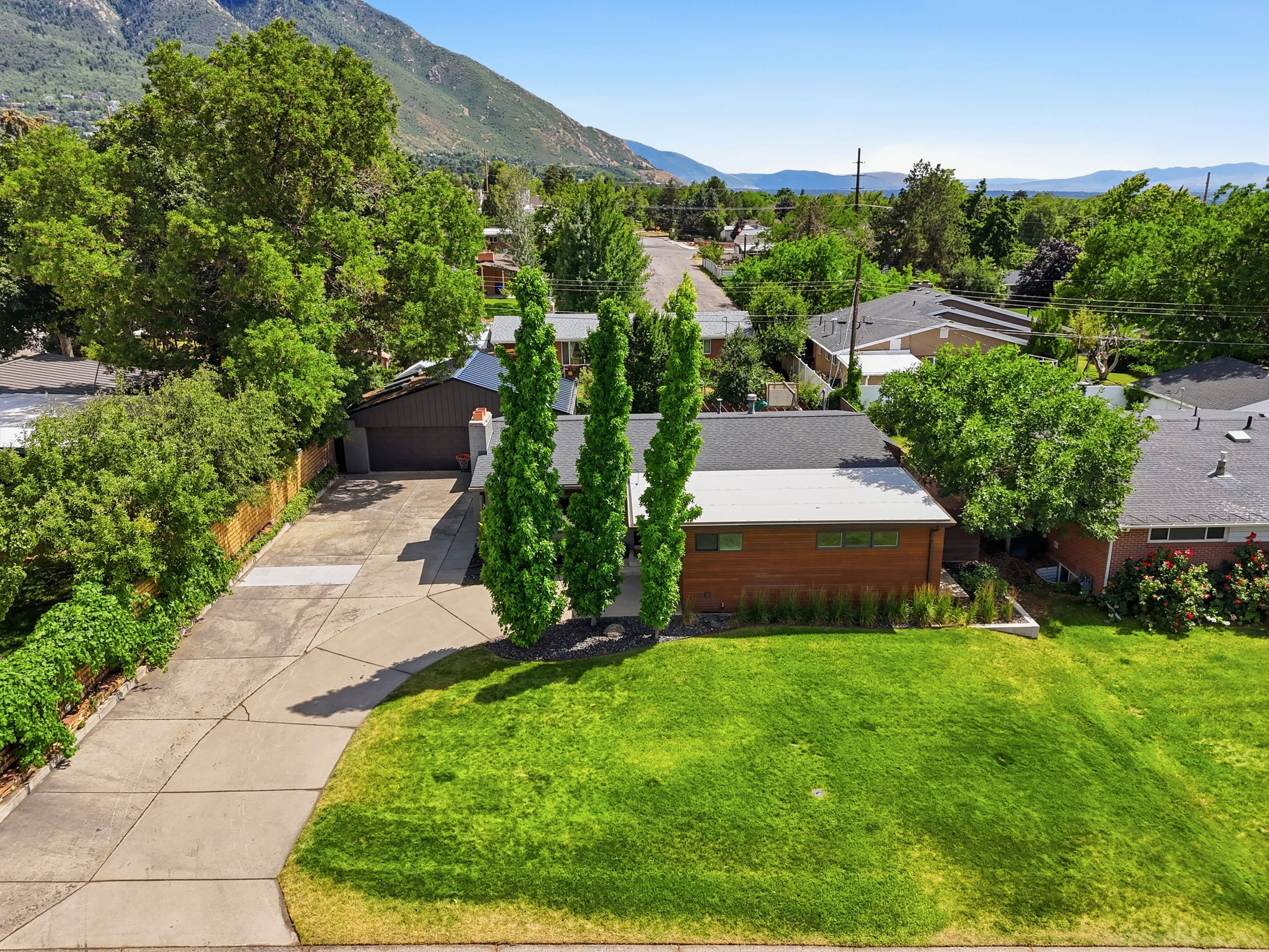 Mid-century modern home featuring wood siding, a flat roofline, and a well-maintained front lawn
