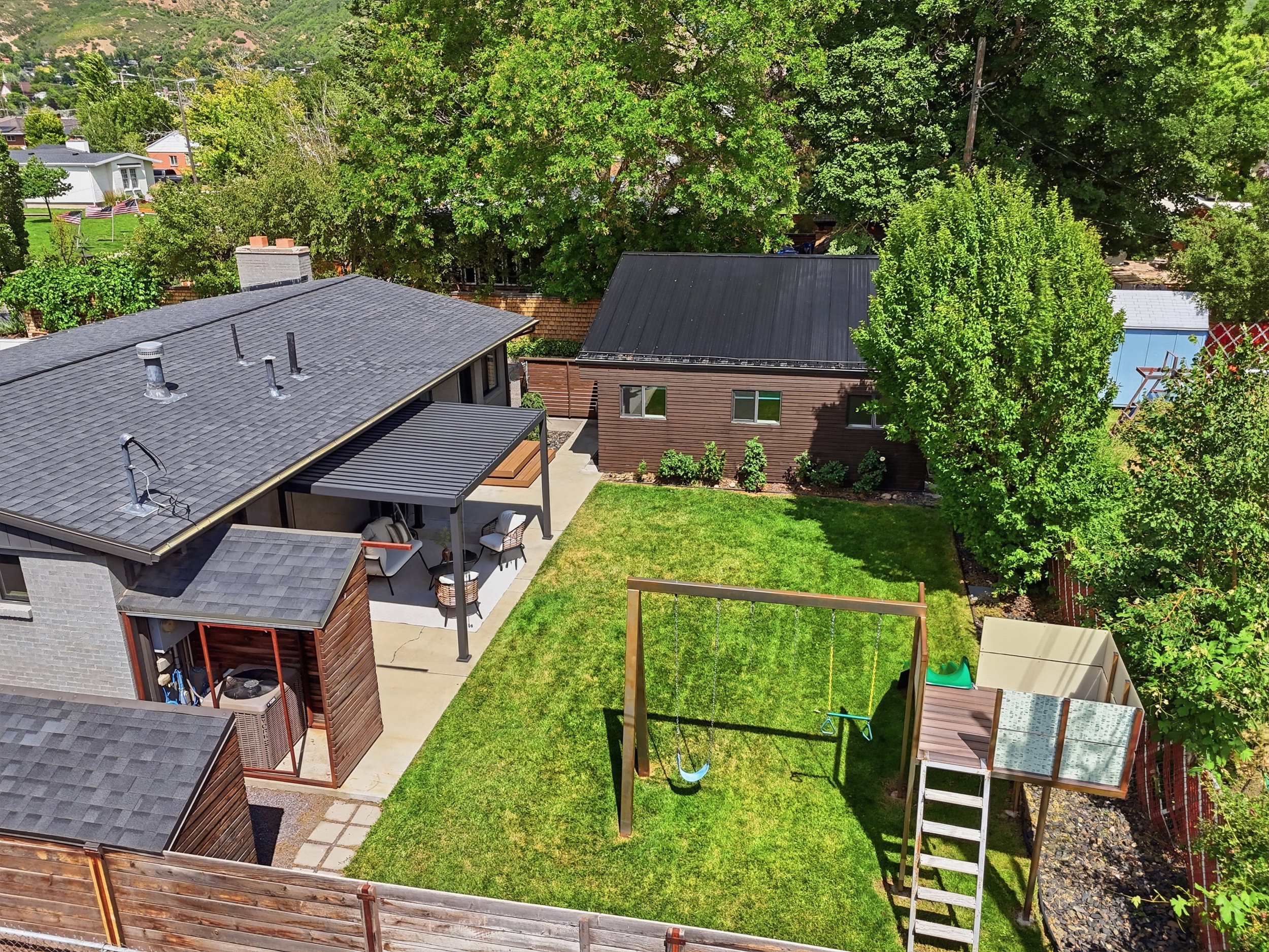 Expansive green lawn with a covered patio, separate outbuilding with a metal roof, and wood fencing