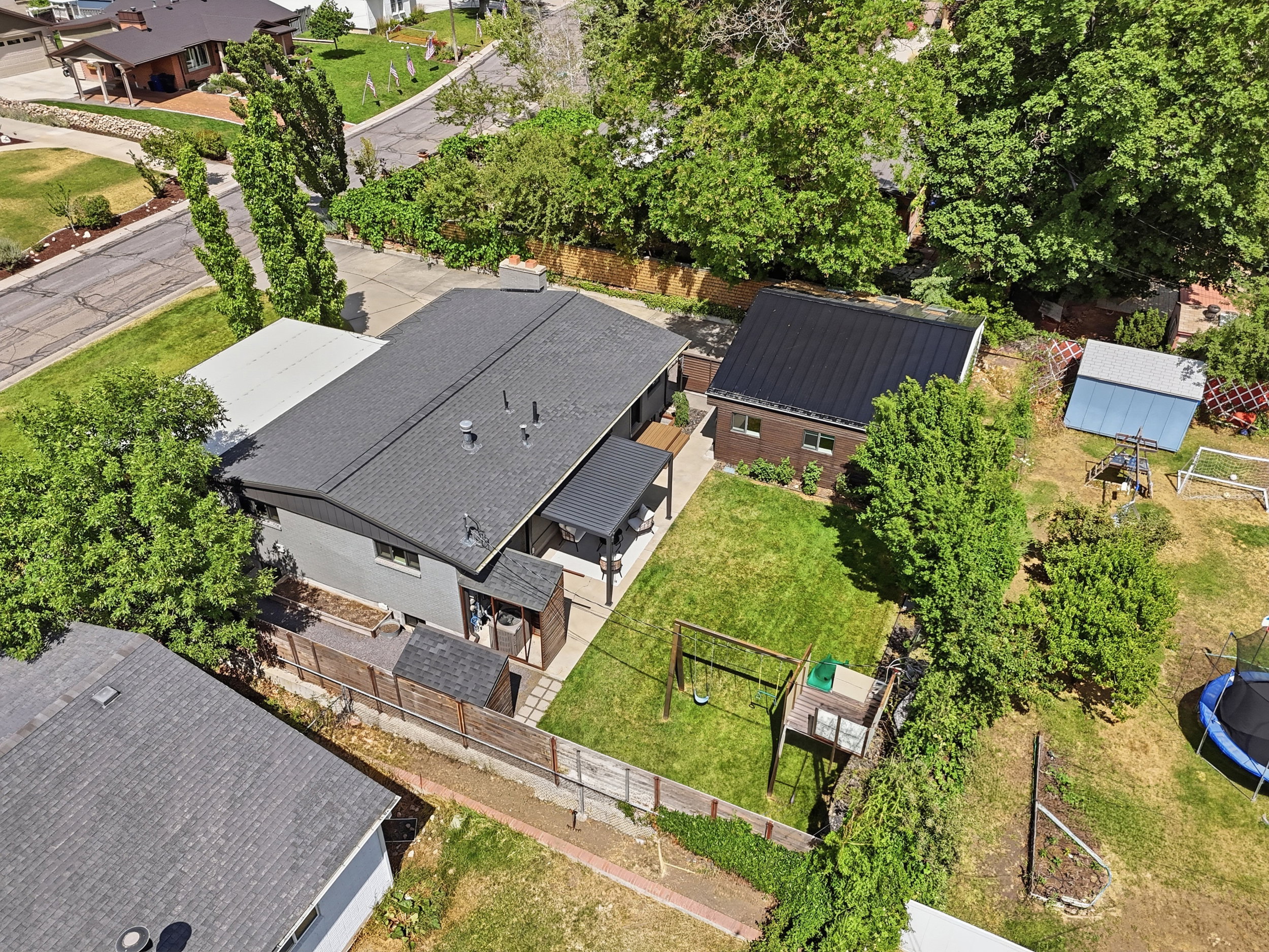 Spacious property featuring a large backyard with a manicured lawn, an expansive patio, and a detached structure with a dark metal roof