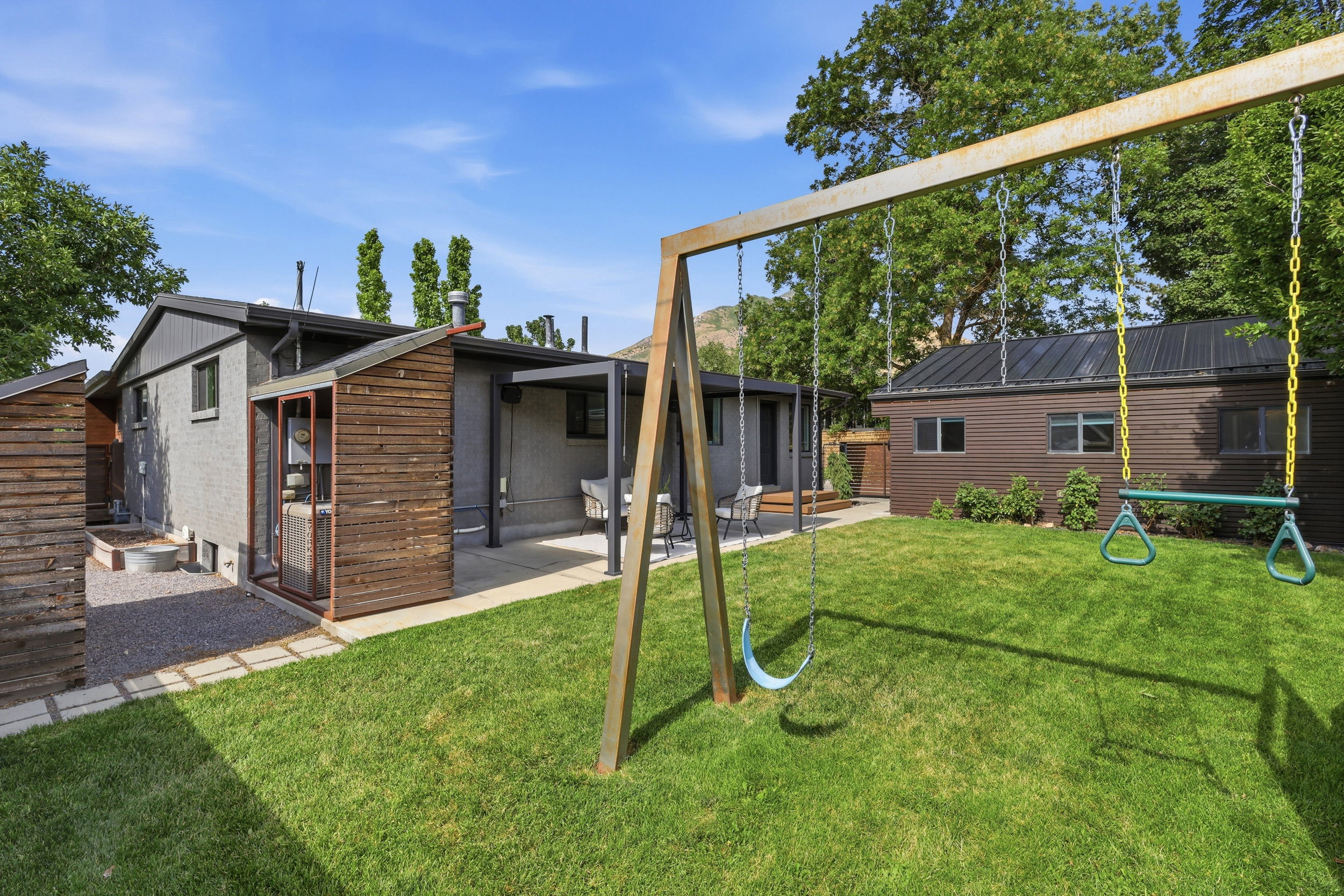 Manicured lawn with a swing set, complemented by a paver stone pathway and a gravel area