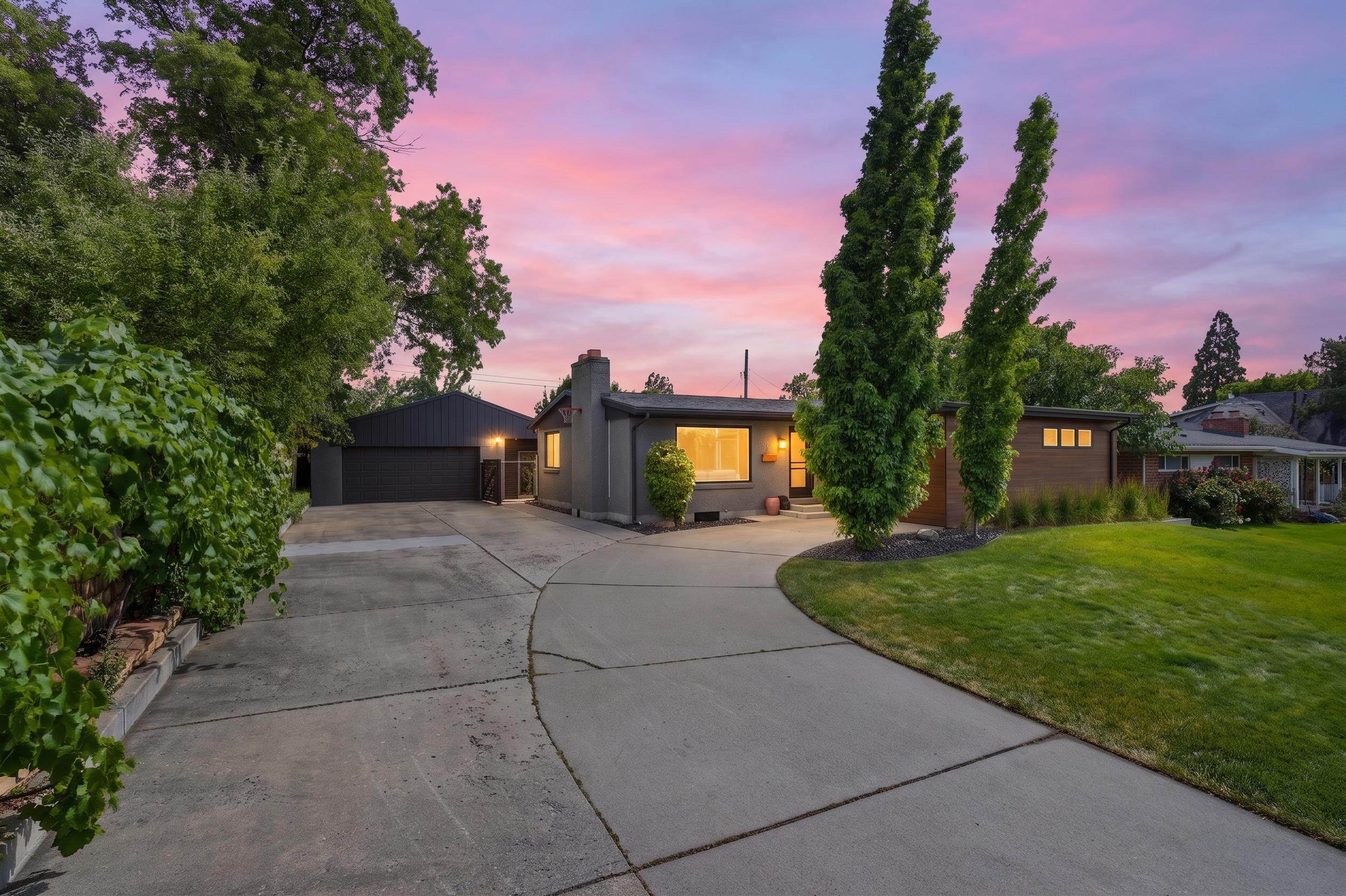 Expansive concrete driveway leading to a residence with a stucco exterior and brick accents