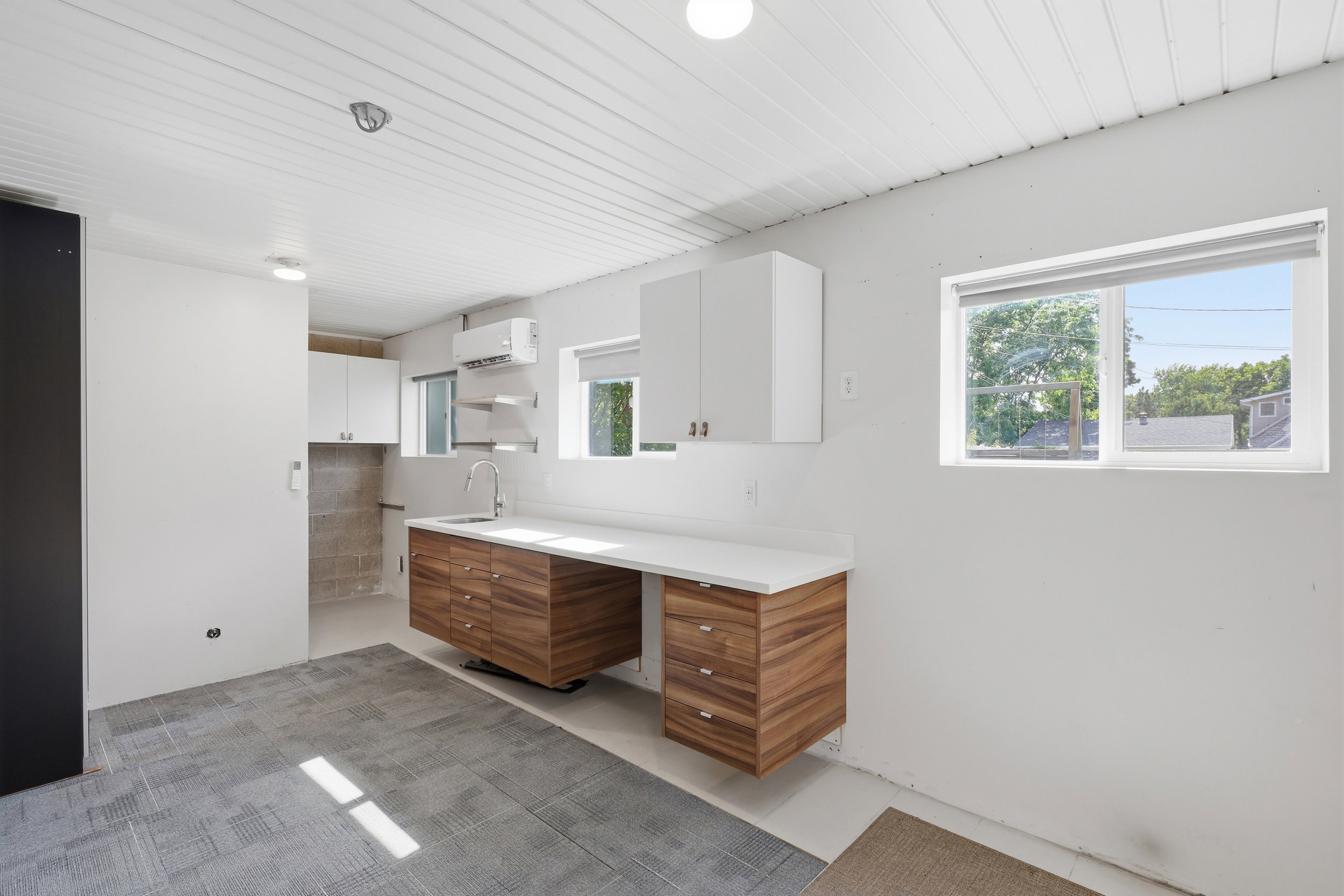 Kitchenette area featuring a stainless steel sink, a contemporary chrome faucet, and white upper cabinetry
