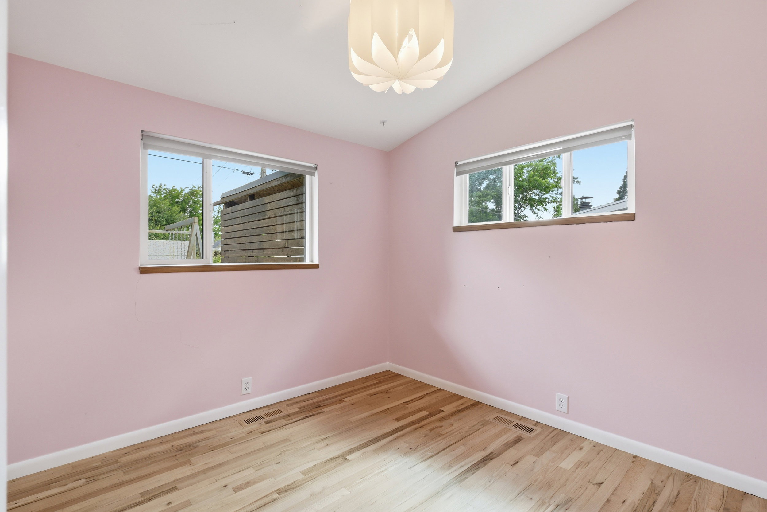 Room featuring wood-finish flooring, two windows with blinds, and a contemporary ceiling light fixture