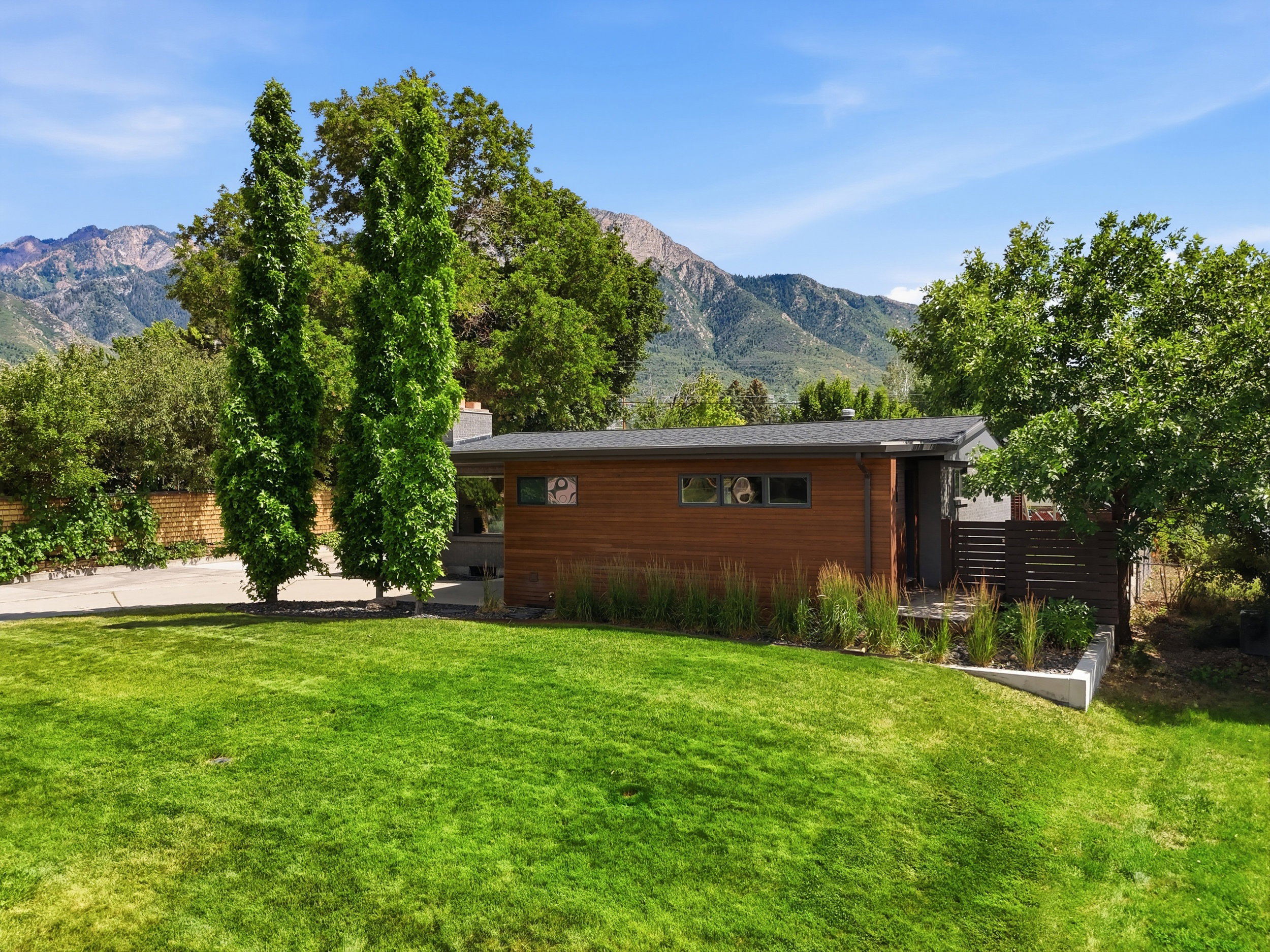 Modern exterior featuring wood-finish siding, a dark gray roof, and a low-profile design